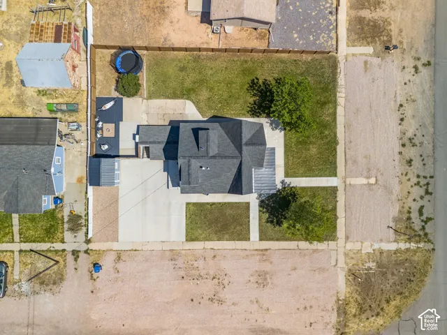 Property featuring a dark shingle roof, concrete driveway, and front lawn