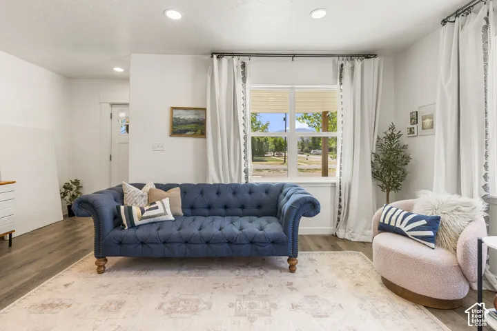 White walls with recessed lighting, wood-finish flooring, and a large window with white trim