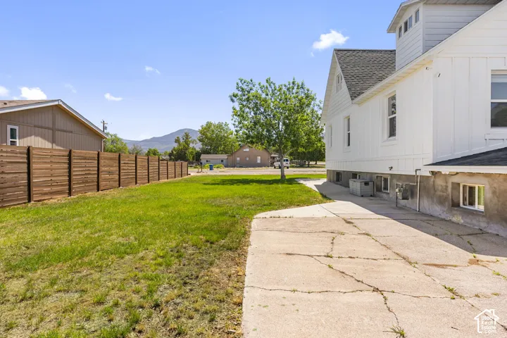 Expansive yard space featuring a manicured lawn, a horizontal wood plank fence, and a concrete pathway