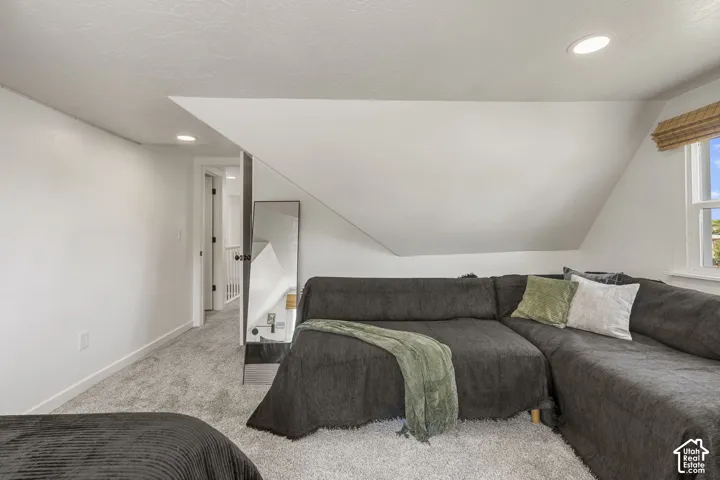Carpeted room with sloped ceilings and recessed lighting