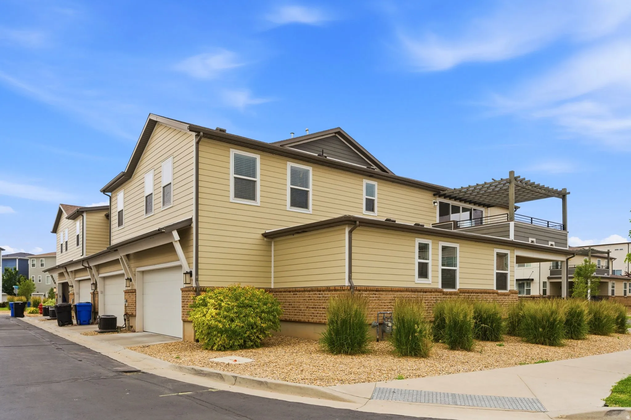 Multi-level townhome featuring a neutral siding exterior and brick accents