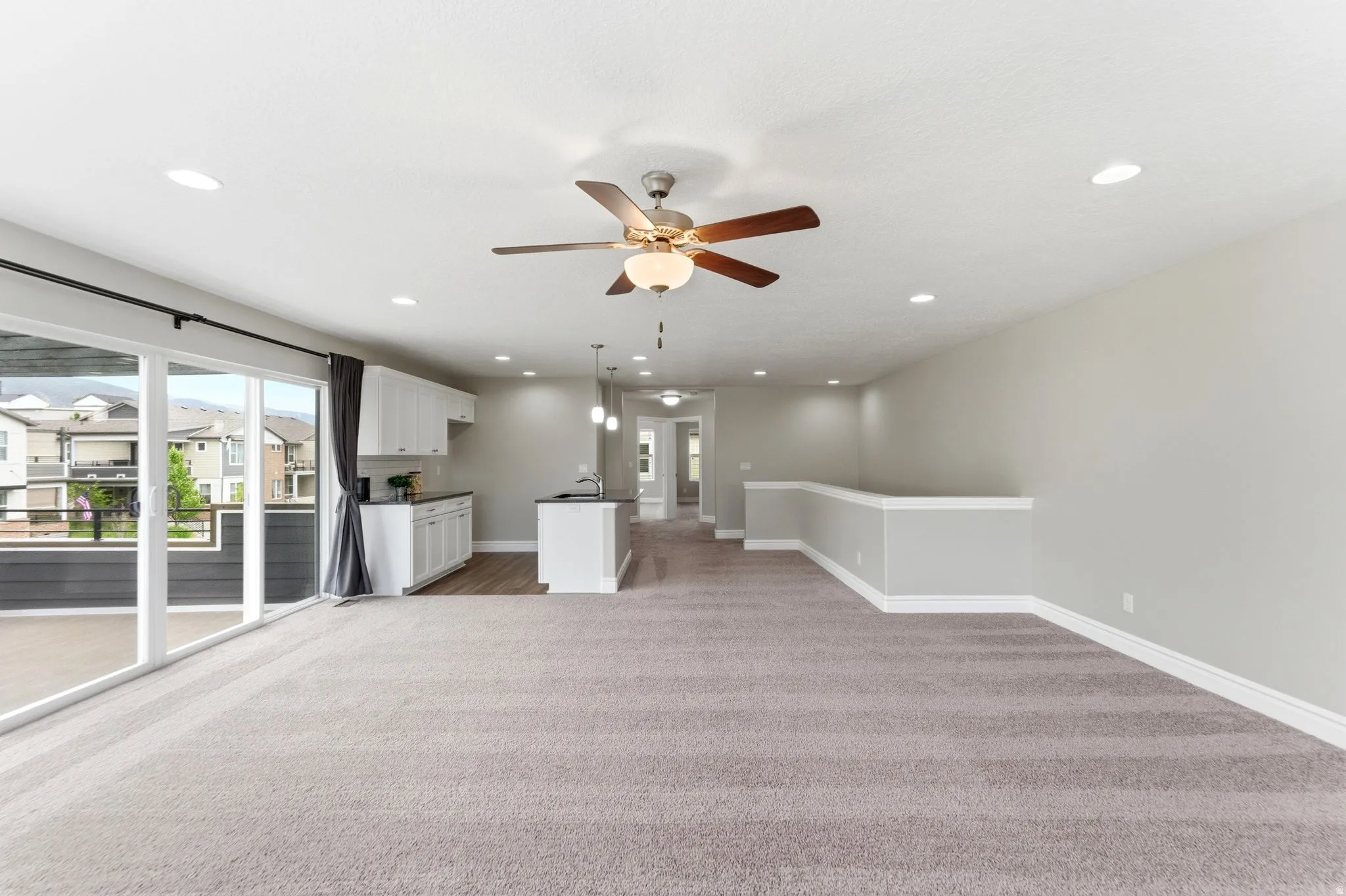 Open-concept living area featuring a neutral color palette, recessed lighting, and a ceiling fan