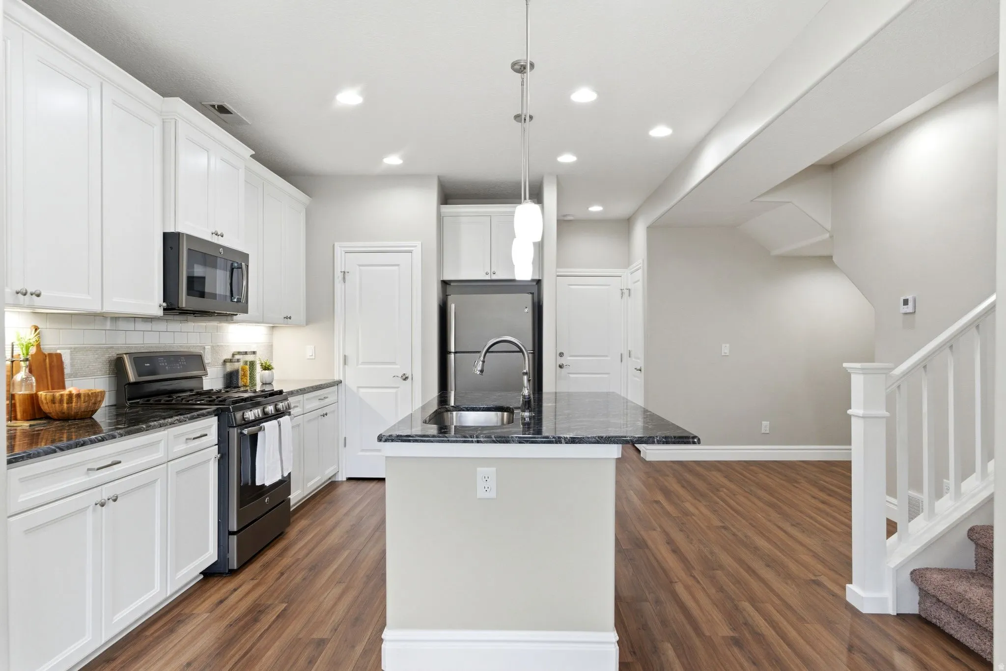 Kitchen featuring white cabinetry, dark stone countertops, stainless steel appliances, and a tile backsplash