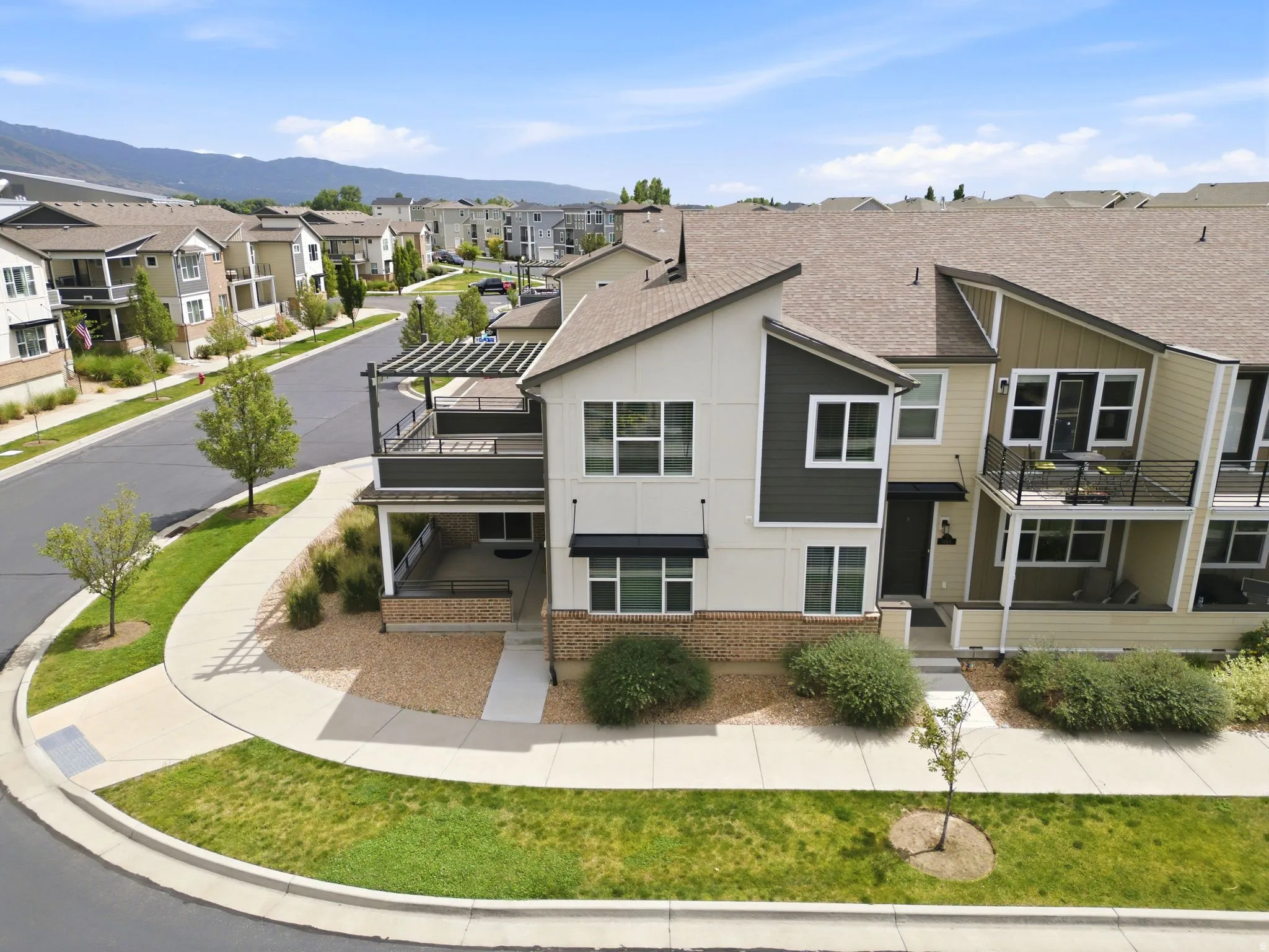 Contemporary multi-level townhome featuring a neutral-toned exterior with dark accent siding and brick detailing