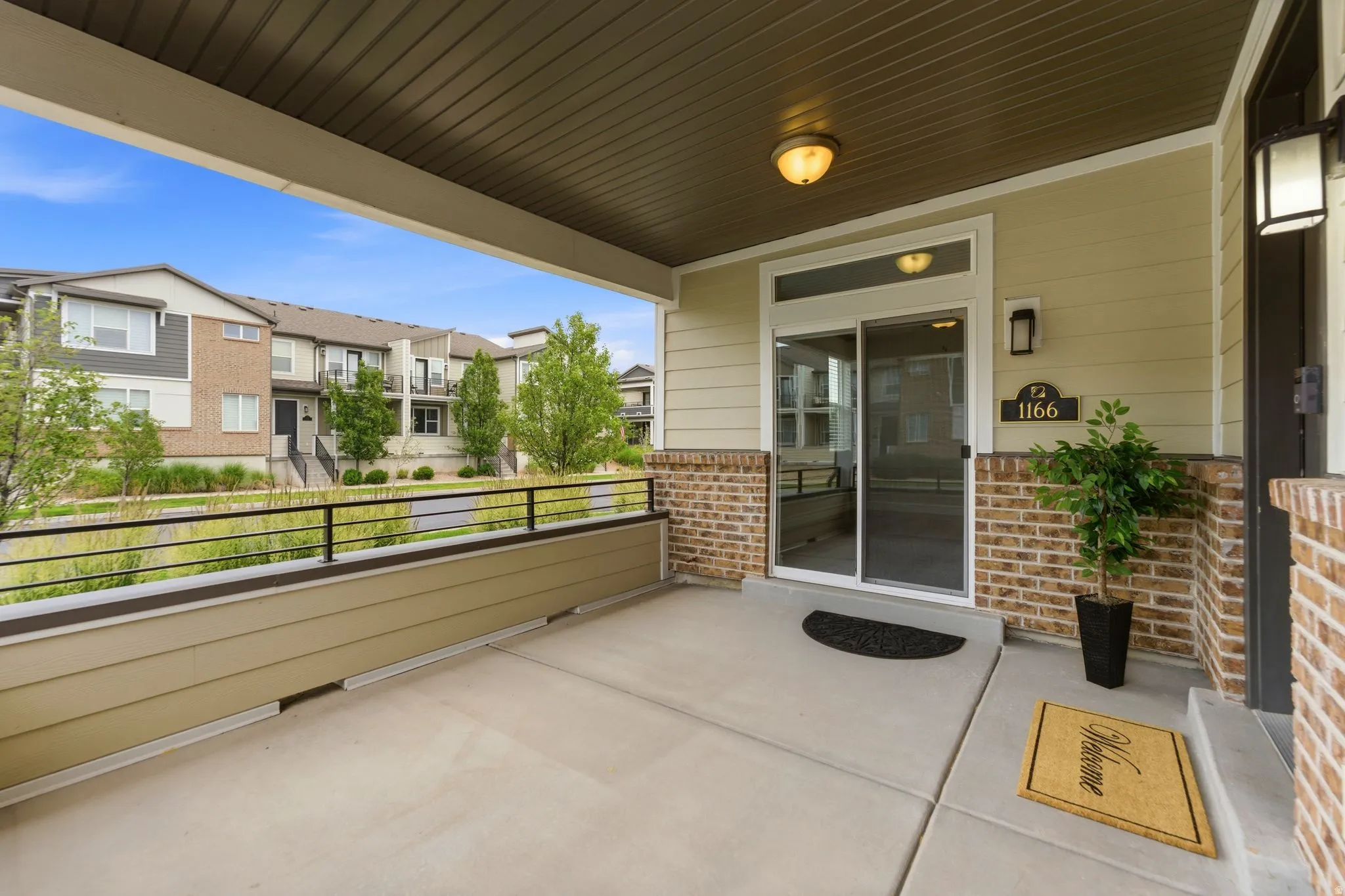 Covered concrete patio entrance with a decorative brick facade