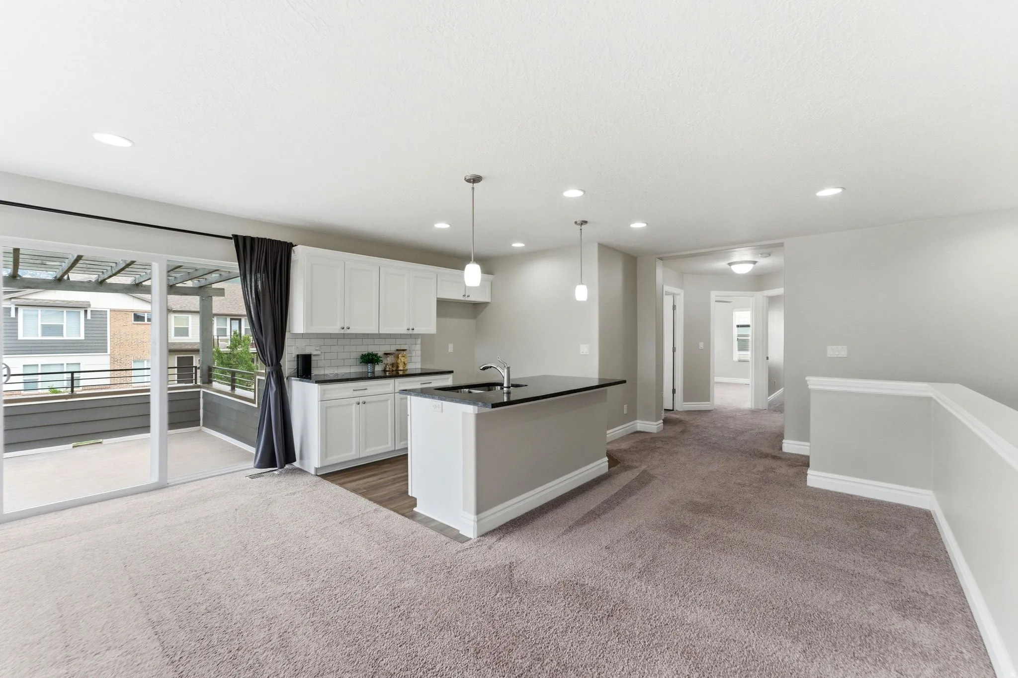 Open-concept living area with a kitchen island featuring a sink and pendant lighting