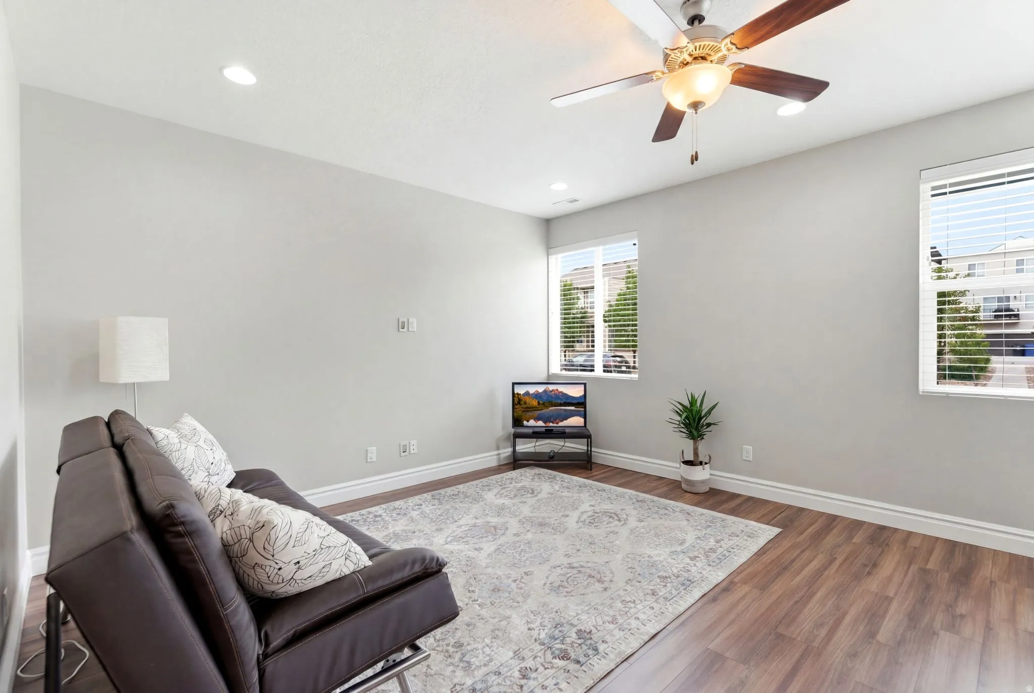 Spacious room featuring wood-finish flooring, light grey walls, and white baseboards