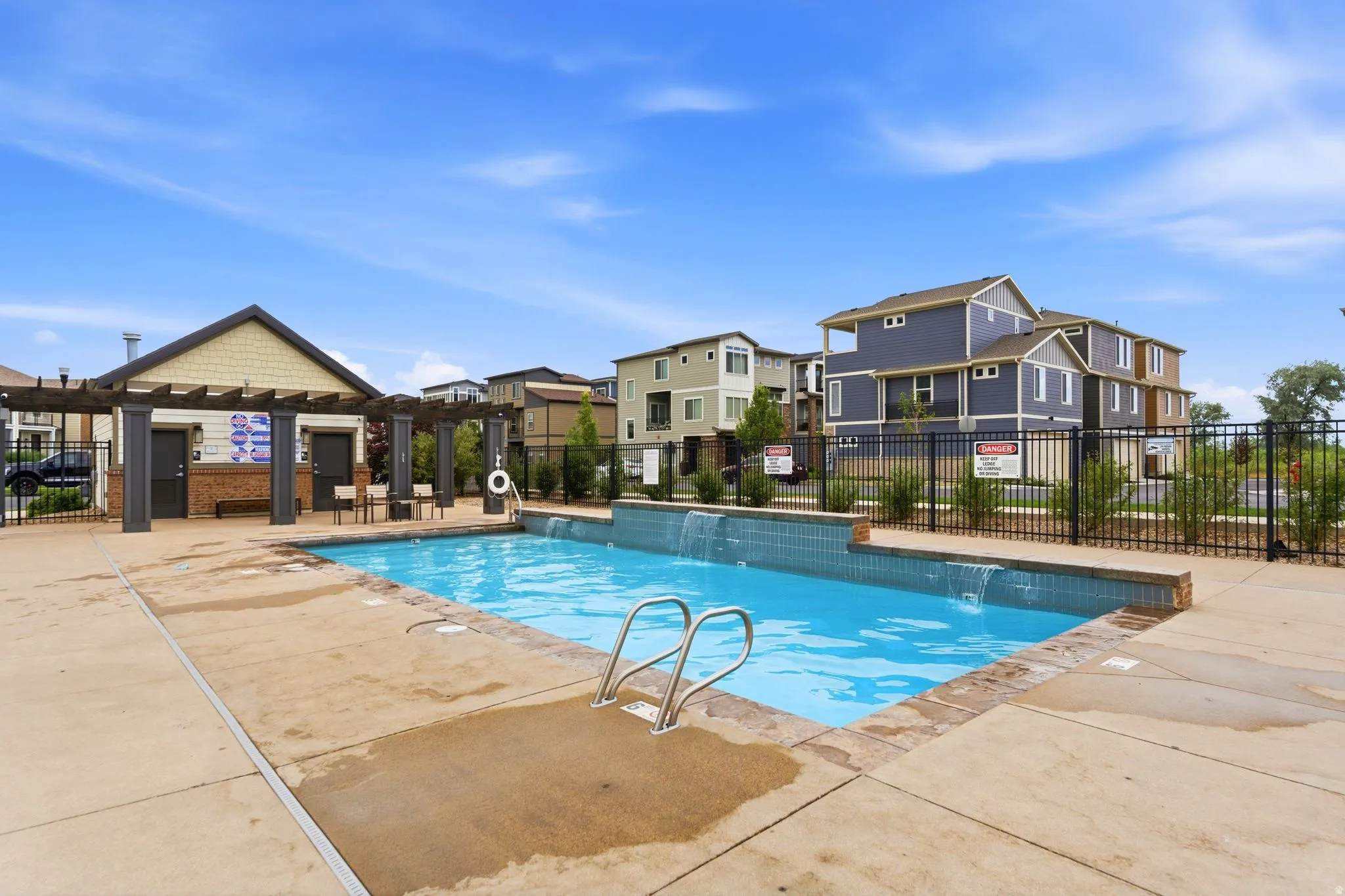 Outdoor swimming pool with integrated waterfall features and a surrounding concrete deck
