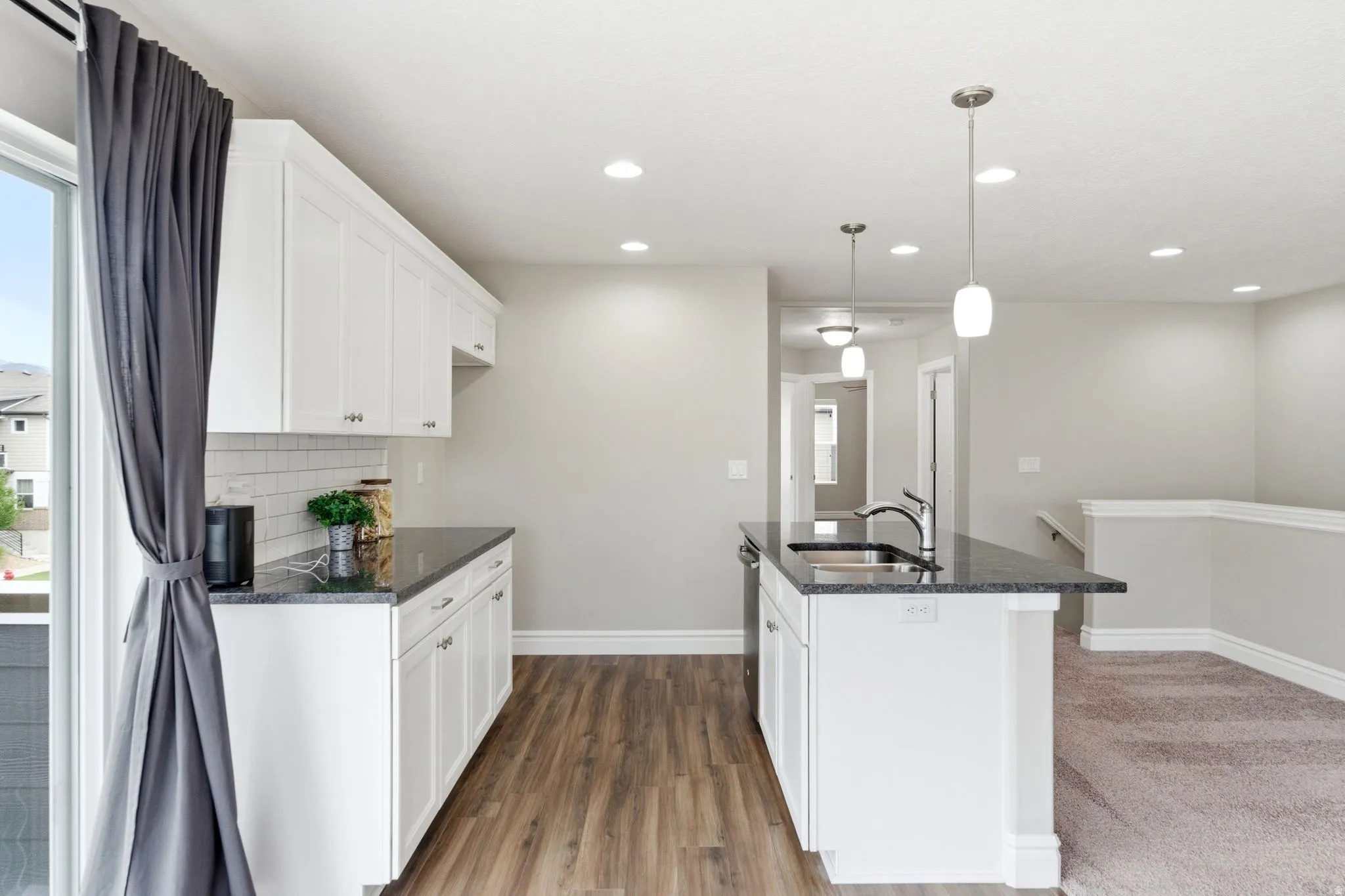 Kitchen featuring white shaker cabinetry, dark stone countertops, and a white subway tile backsplash
