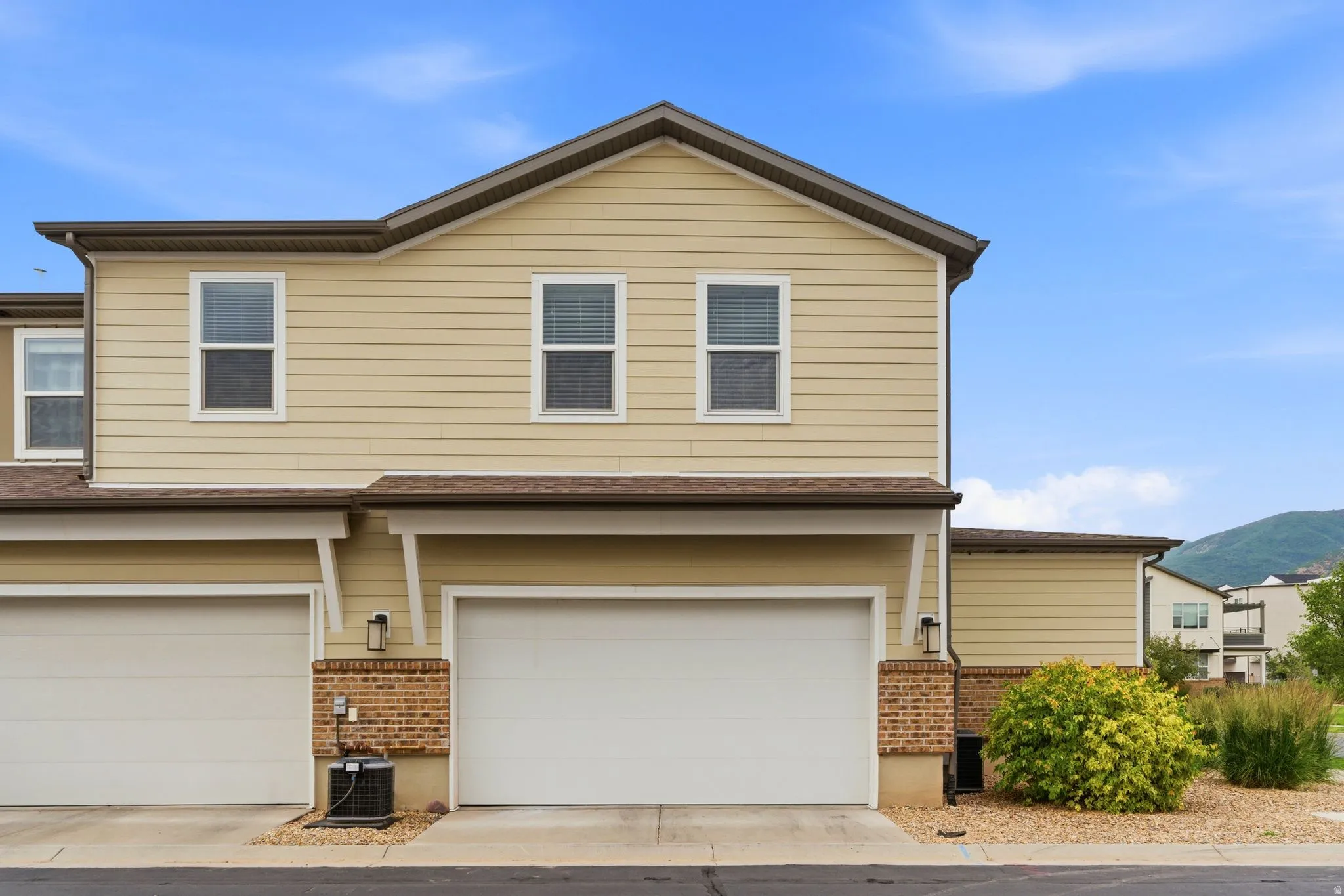 Exterior facade featuring horizontal siding, multiple windows, and integrated garage doors