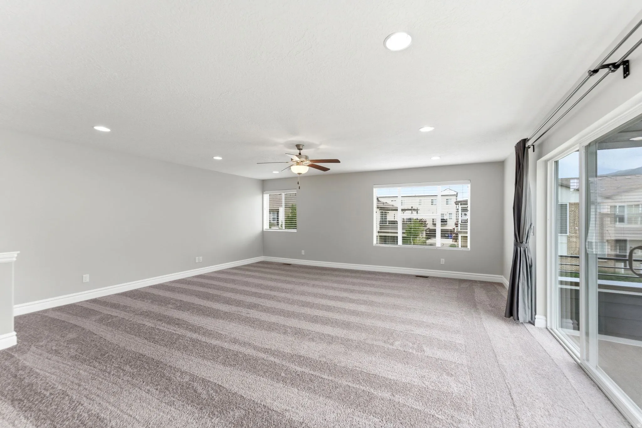 Spacious room featuring neutral carpeting, recessed lighting, and a ceiling fan