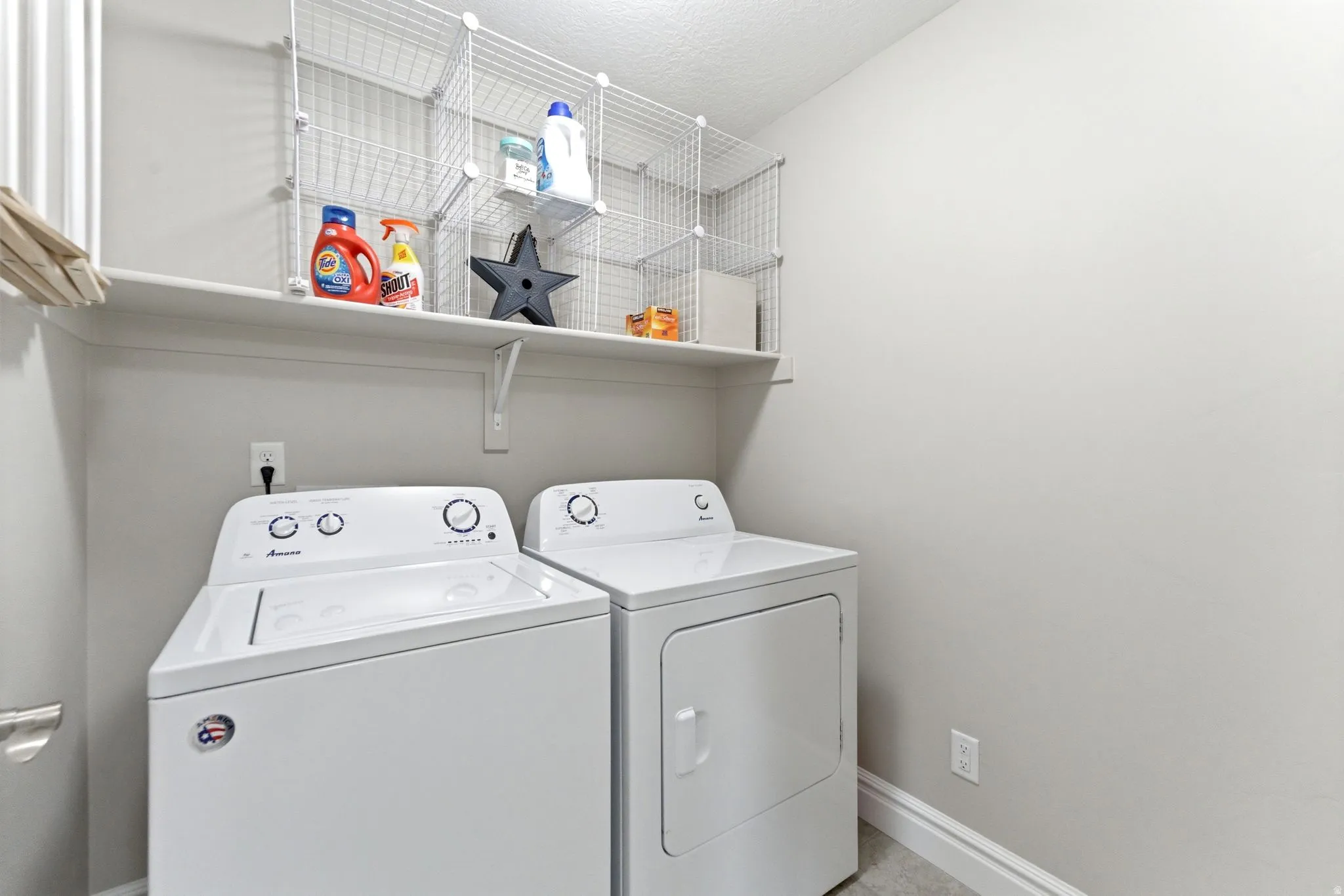 Dedicated utility area featuring white appliances, a wall-mounted shelf, and wire storage cubbies