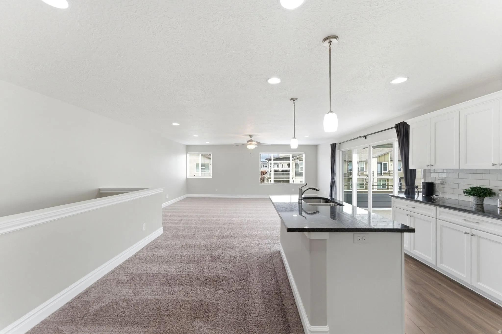 Modern kitchen featuring white cabinetry, subway tile backsplash, and dark countertops