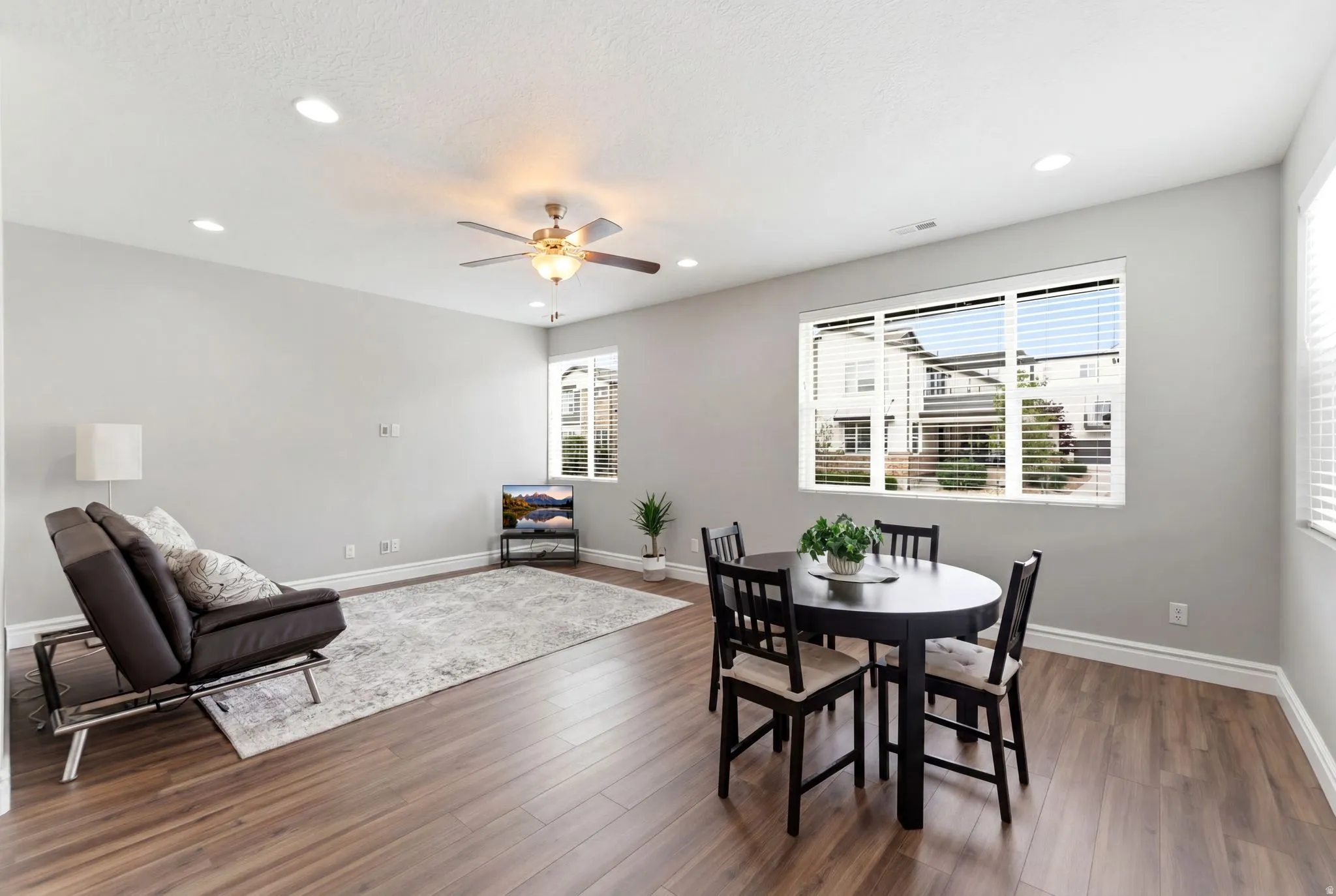 Open-concept living and dining area featuring wood-finish flooring, recessed lighting, and a ceiling fan