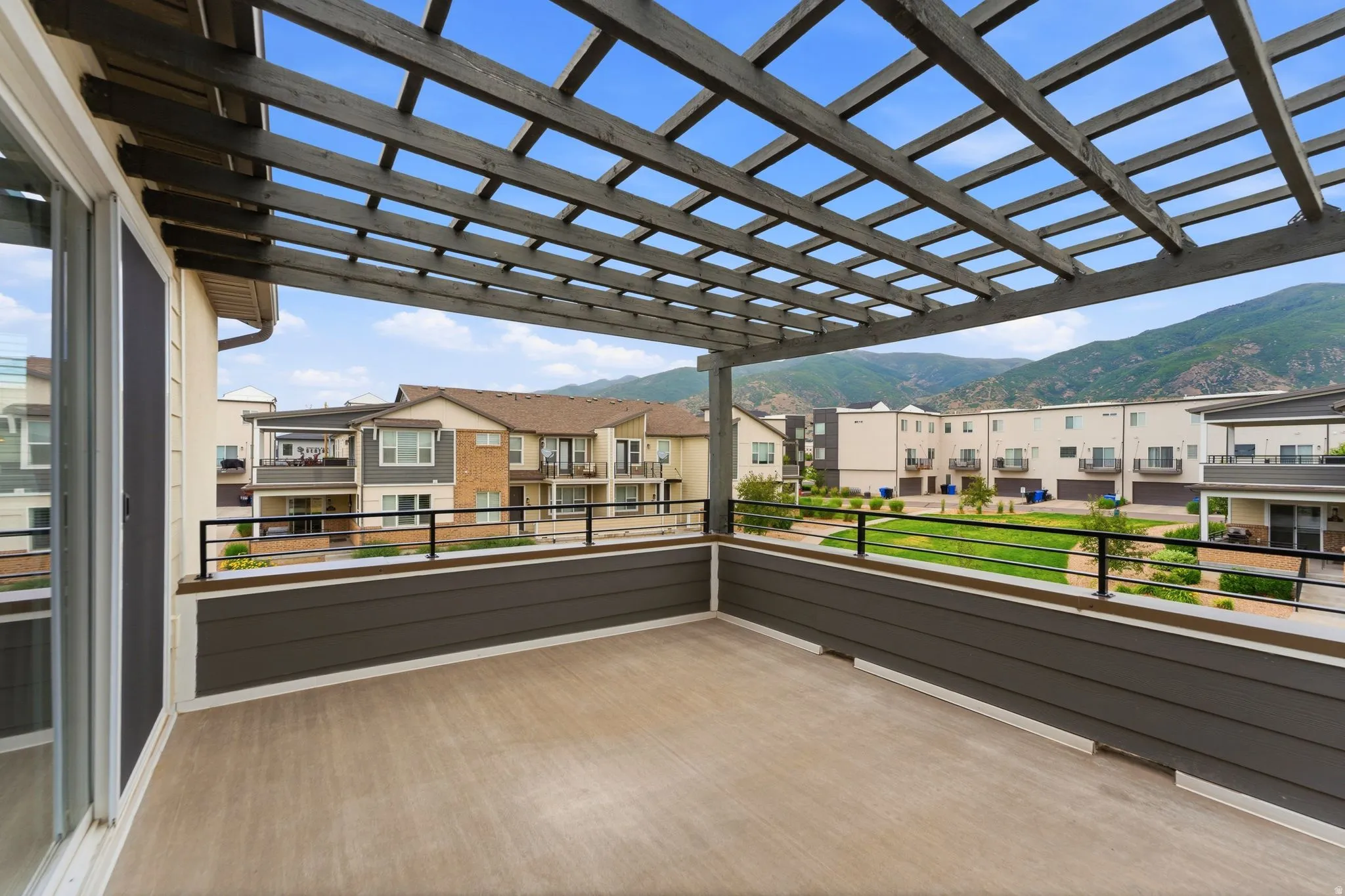 Expansive exterior deck featuring a slatted pergola, composite decking, and dark horizontal siding