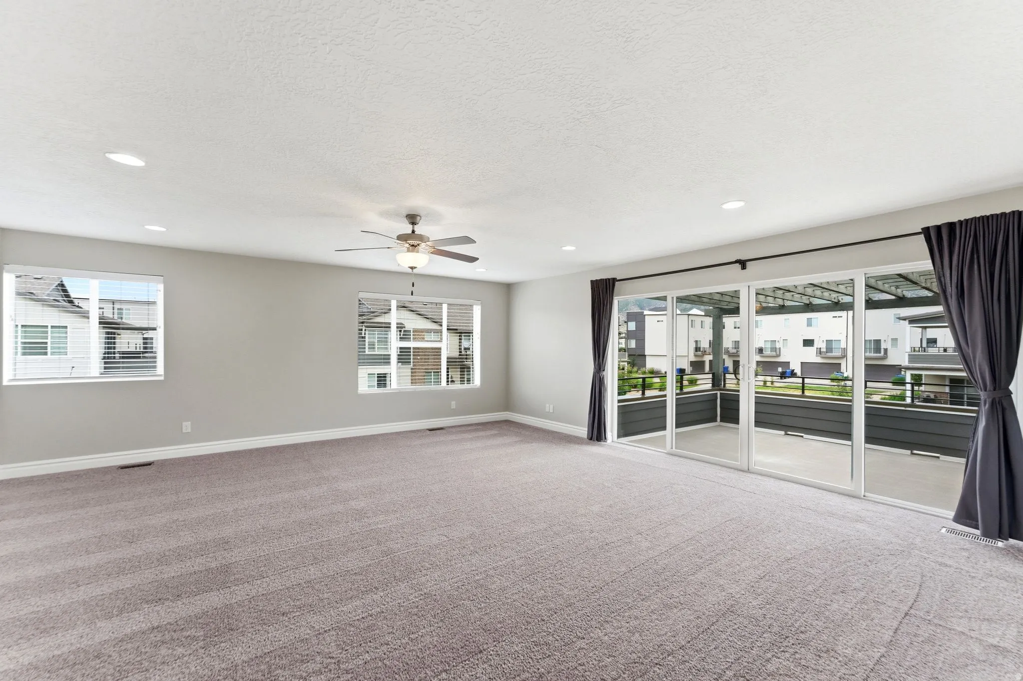 Spacious room featuring neutral carpet flooring, recessed lighting, and a ceiling fan