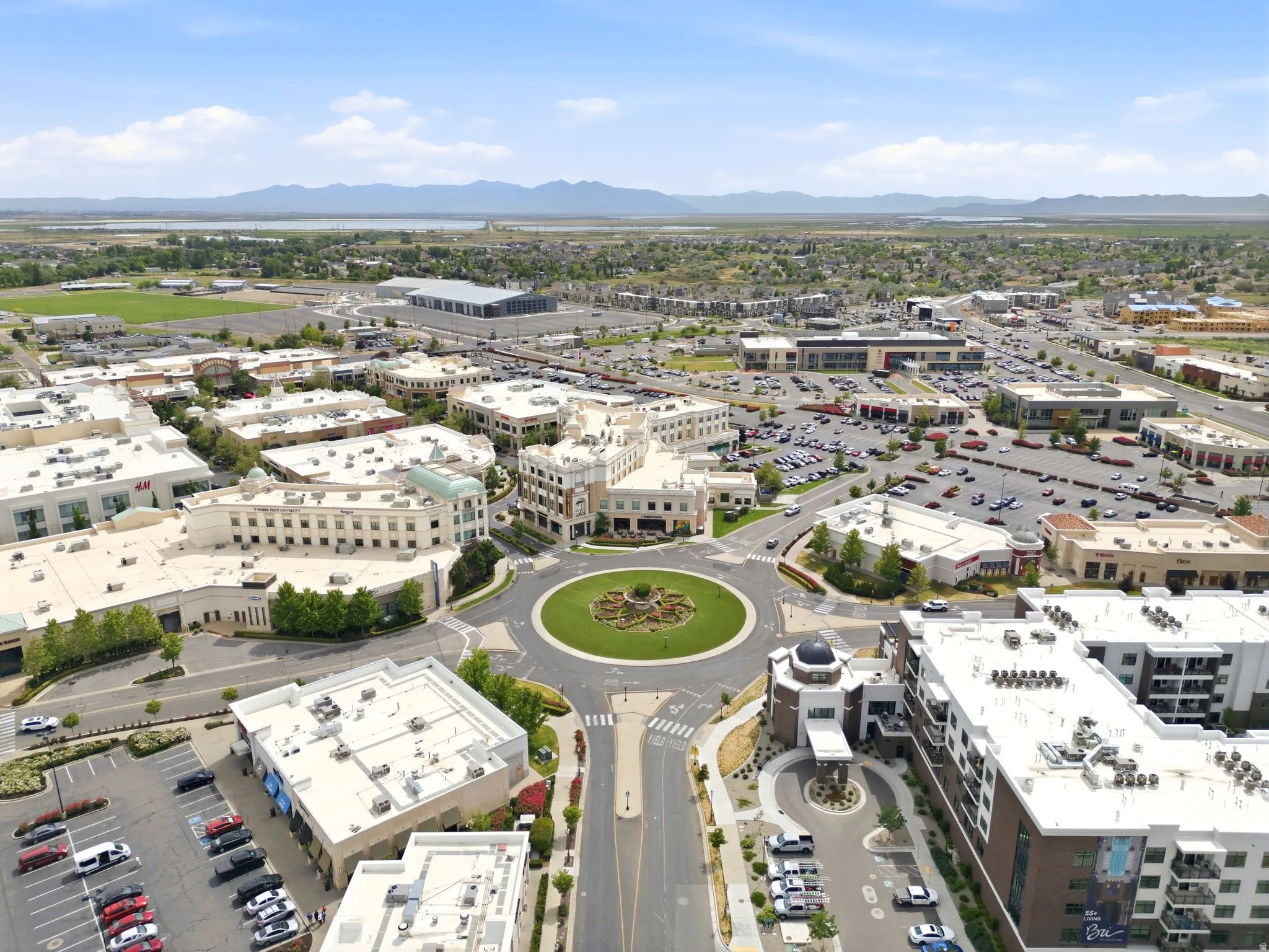 Aerial perspective showcasing a vibrant commercial and residential district with a central roundabout featuring a landscaped island