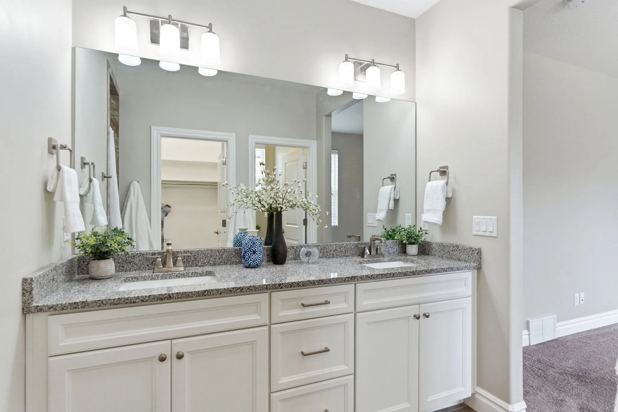 Double vanity with white cabinetry, granite countertop, and undermount sinks
