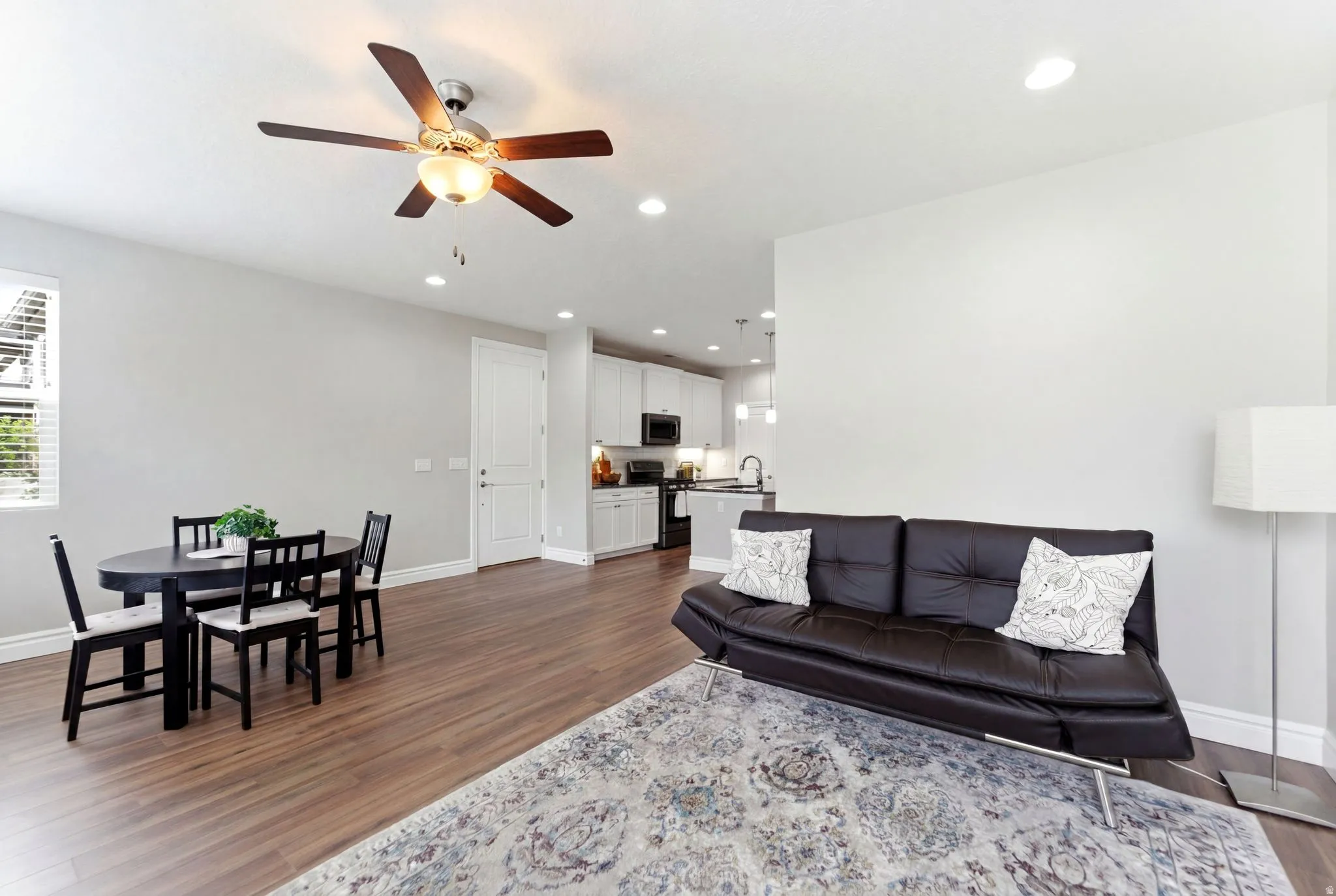 Open-concept living space featuring wood-finish flooring, recessed lighting, and a ceiling fan with light fixture