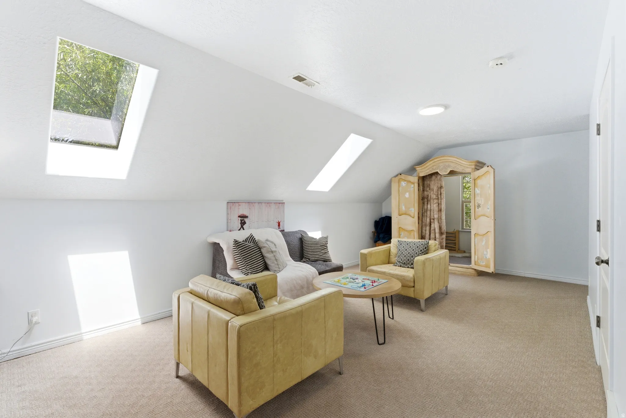 Attic space featuring two skylights, recessed lighting, and sloped ceilings