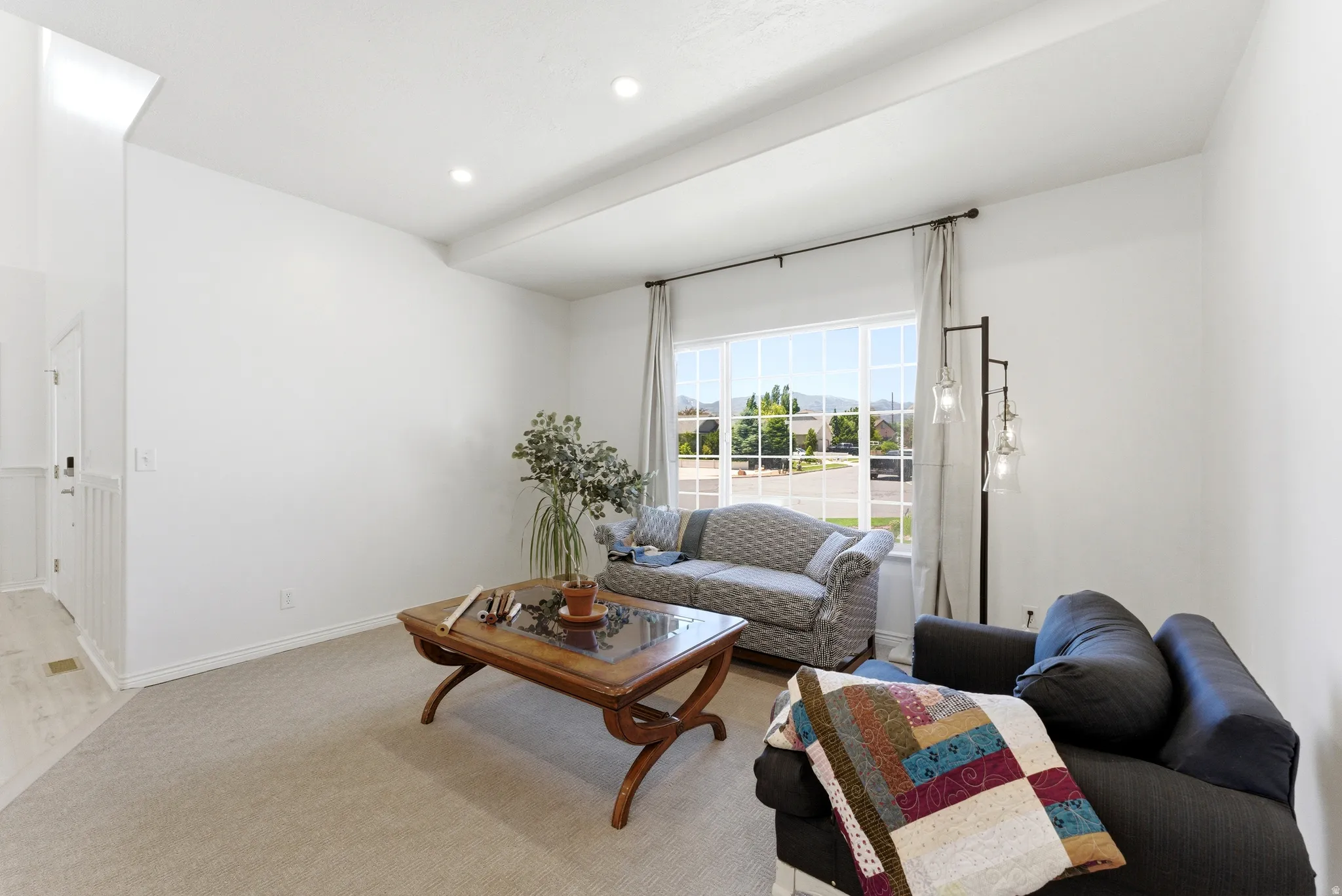Living area featuring a large picture window, recessed lighting, and neutral carpeting