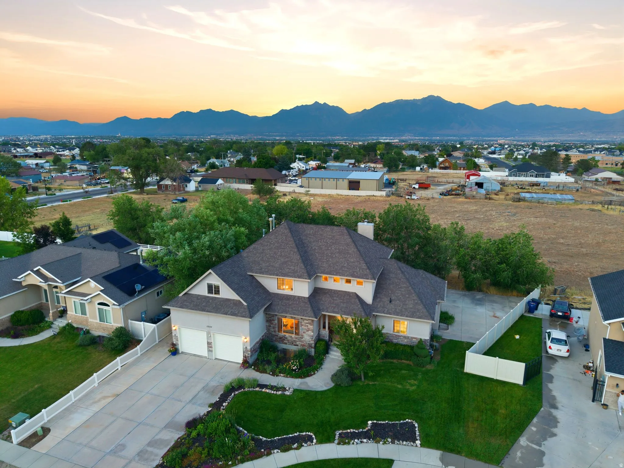 Expansive property featuring a multi-gable roofline, stone and siding exterior, two-car garage, and mature landscaping