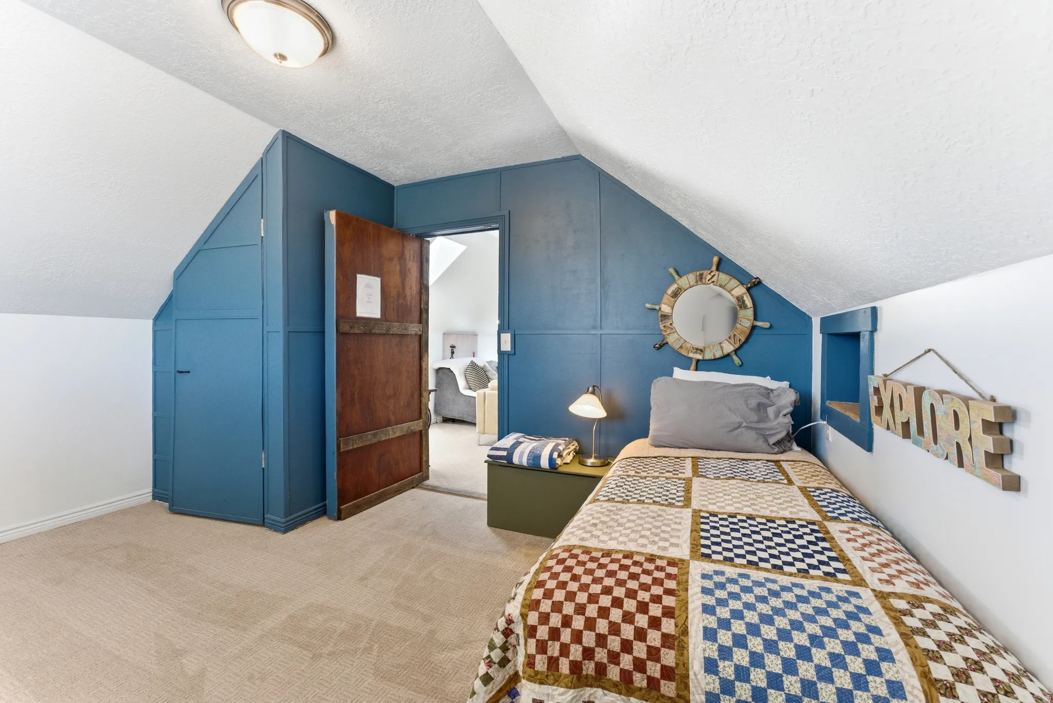 Sloped ceiling room featuring textured white ceilings and light-colored carpeting