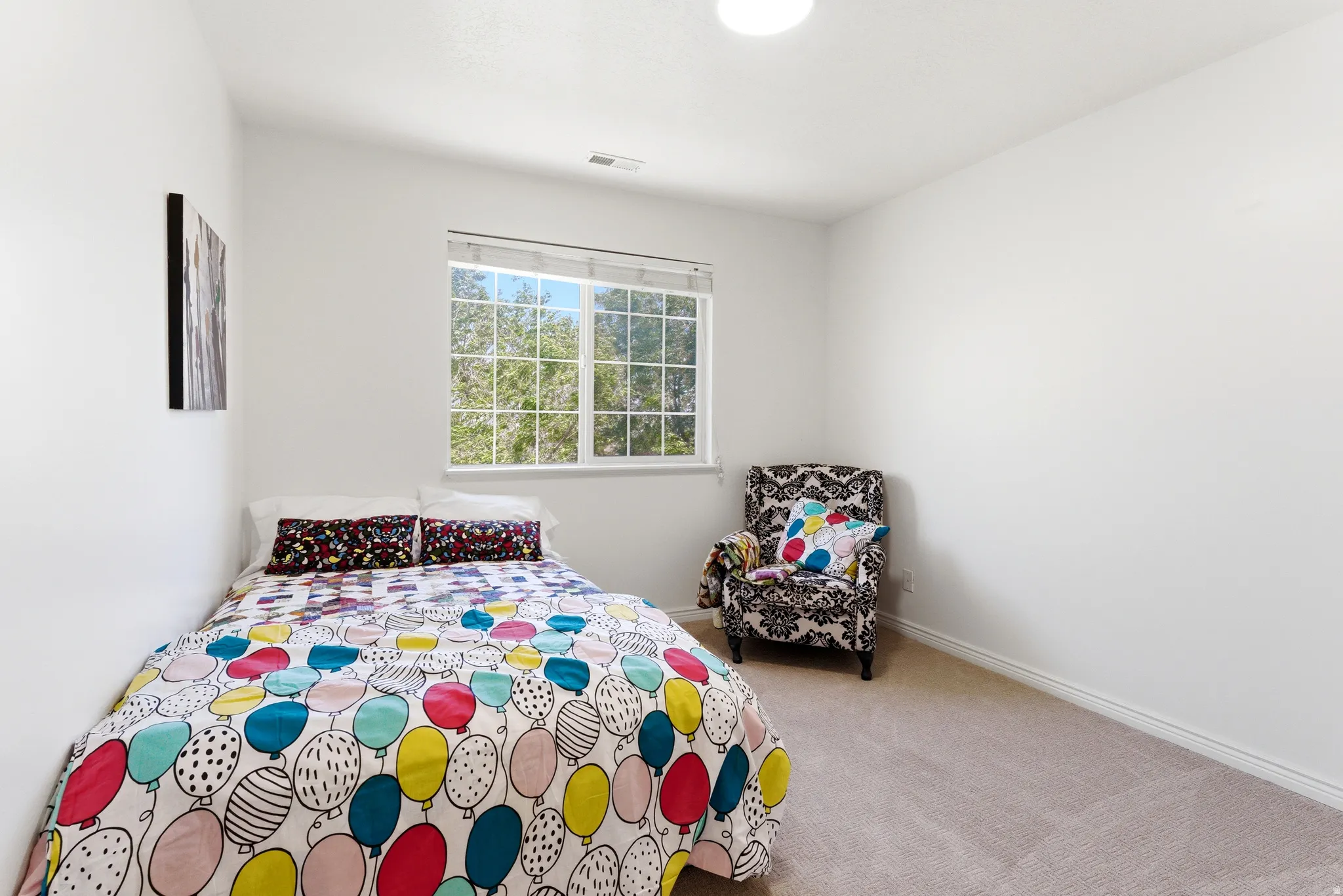Bright room featuring a large window with white muntins, light-colored carpeting, white baseboards, and a flush-mount ceiling light