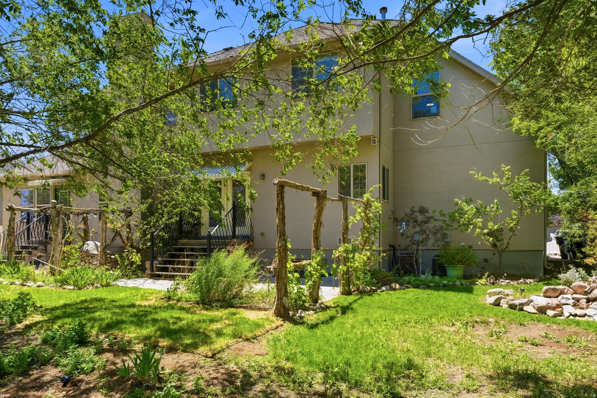 Stucco exterior residence with multiple windows and mature trees