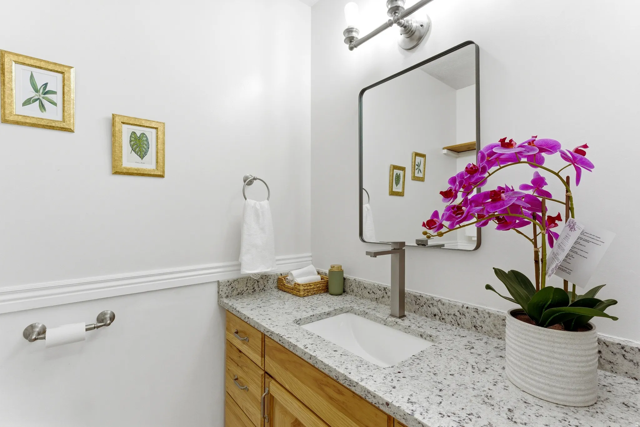 Bathroom vanity featuring a speckled countertop, undermount sink, and brushed nickel faucet