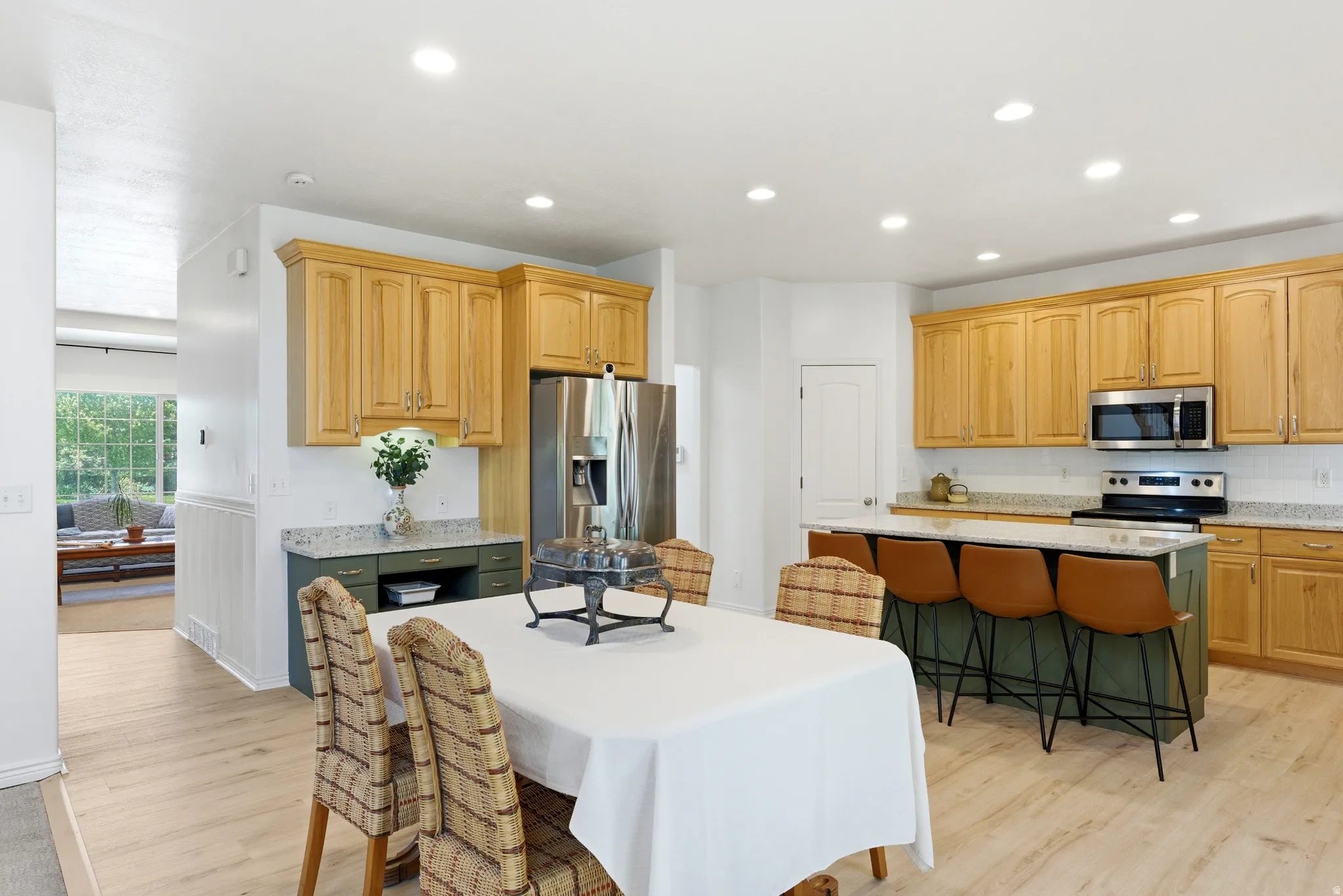 Open-concept kitchen and dining area featuring light wood-finish flooring, recessed lighting, and a kitchen island with seating