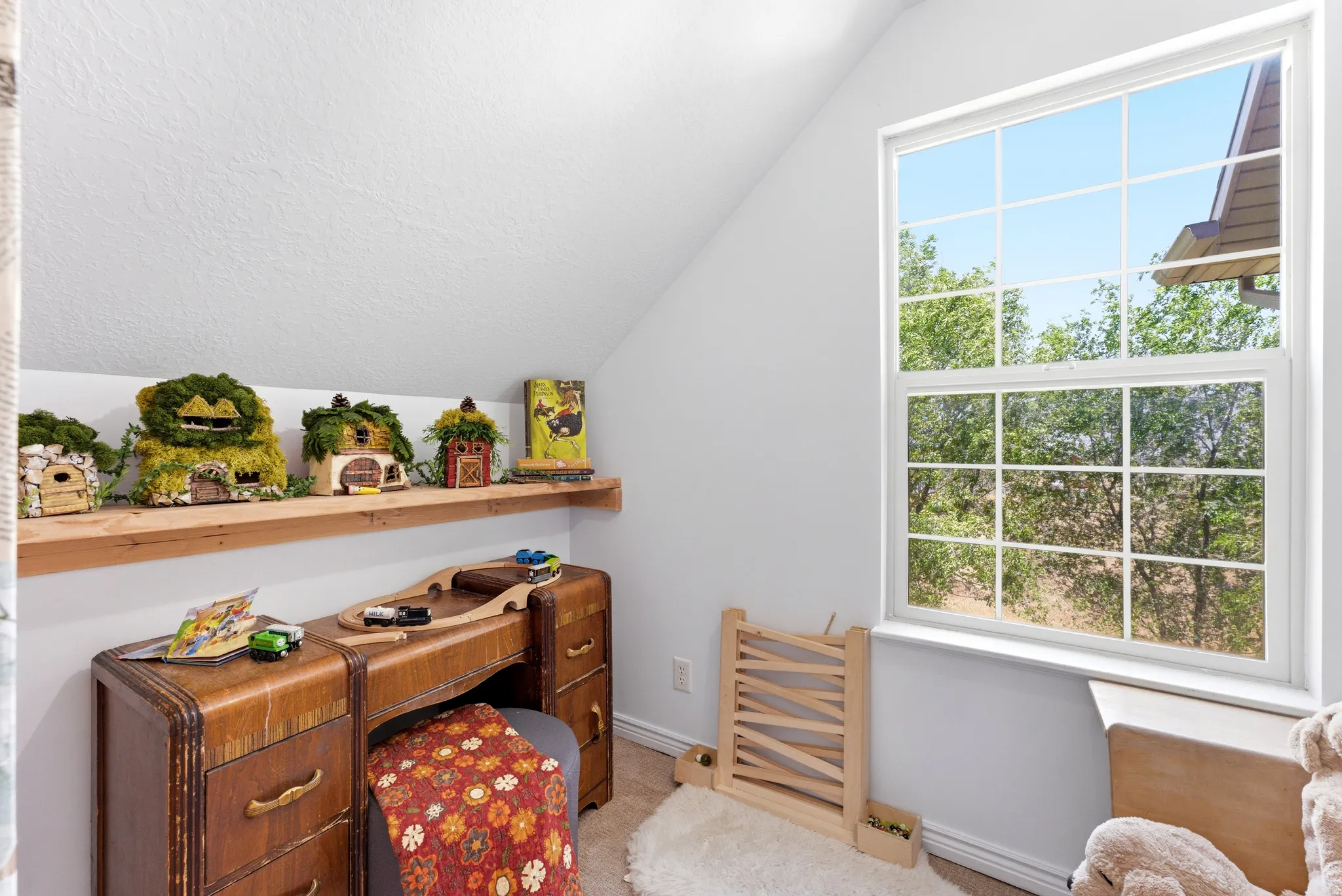Bright window with grid-patterned panes, sloped ceiling, and wood-finish shelving