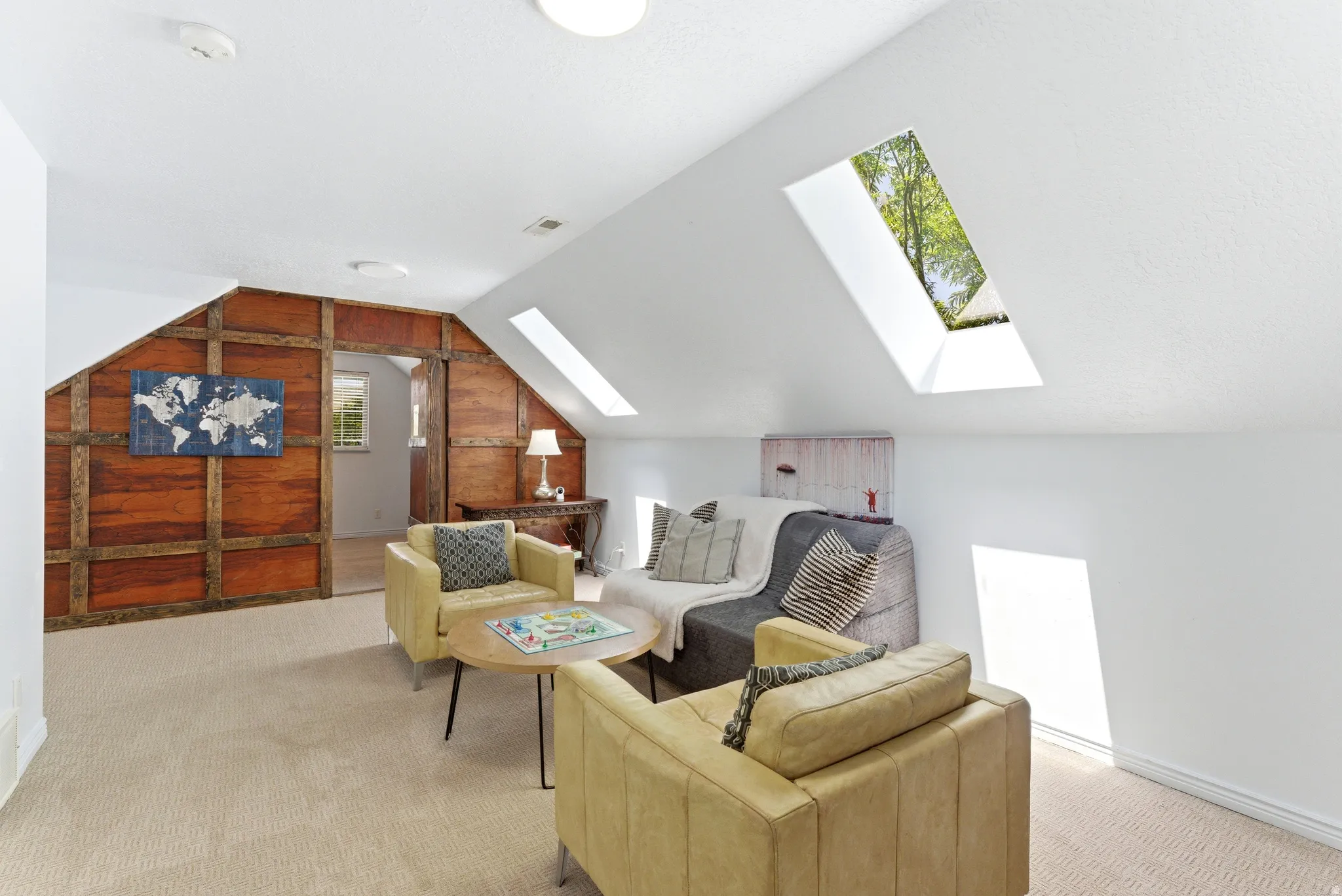 Carpeted attic space featuring white sloped ceilings with skylights