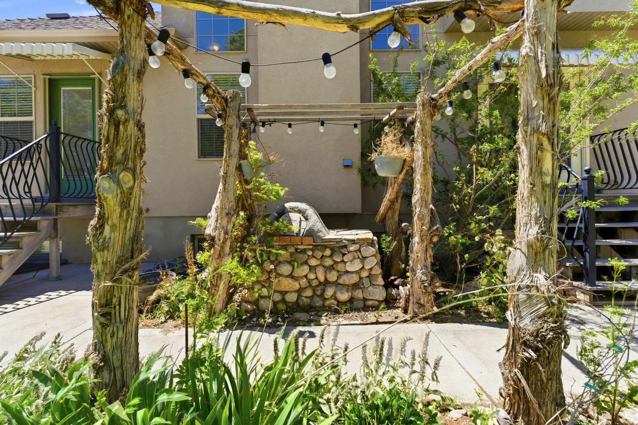 Outdoor entertainment area featuring a custom pergola, string lighting, and an integrated stone fire pit