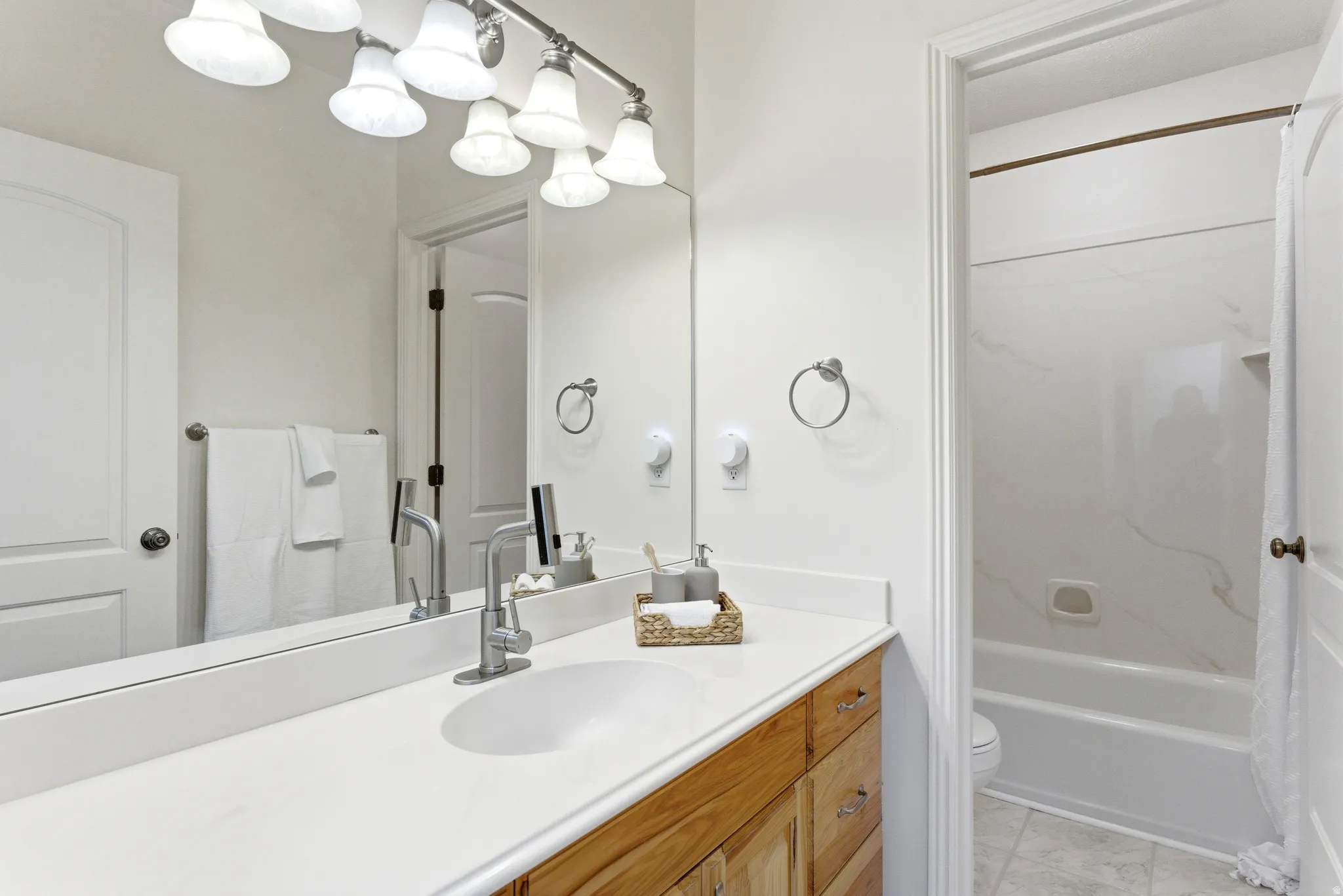 Bathroom vanity with a white countertop, undermount sink, and wood-finish cabinetry