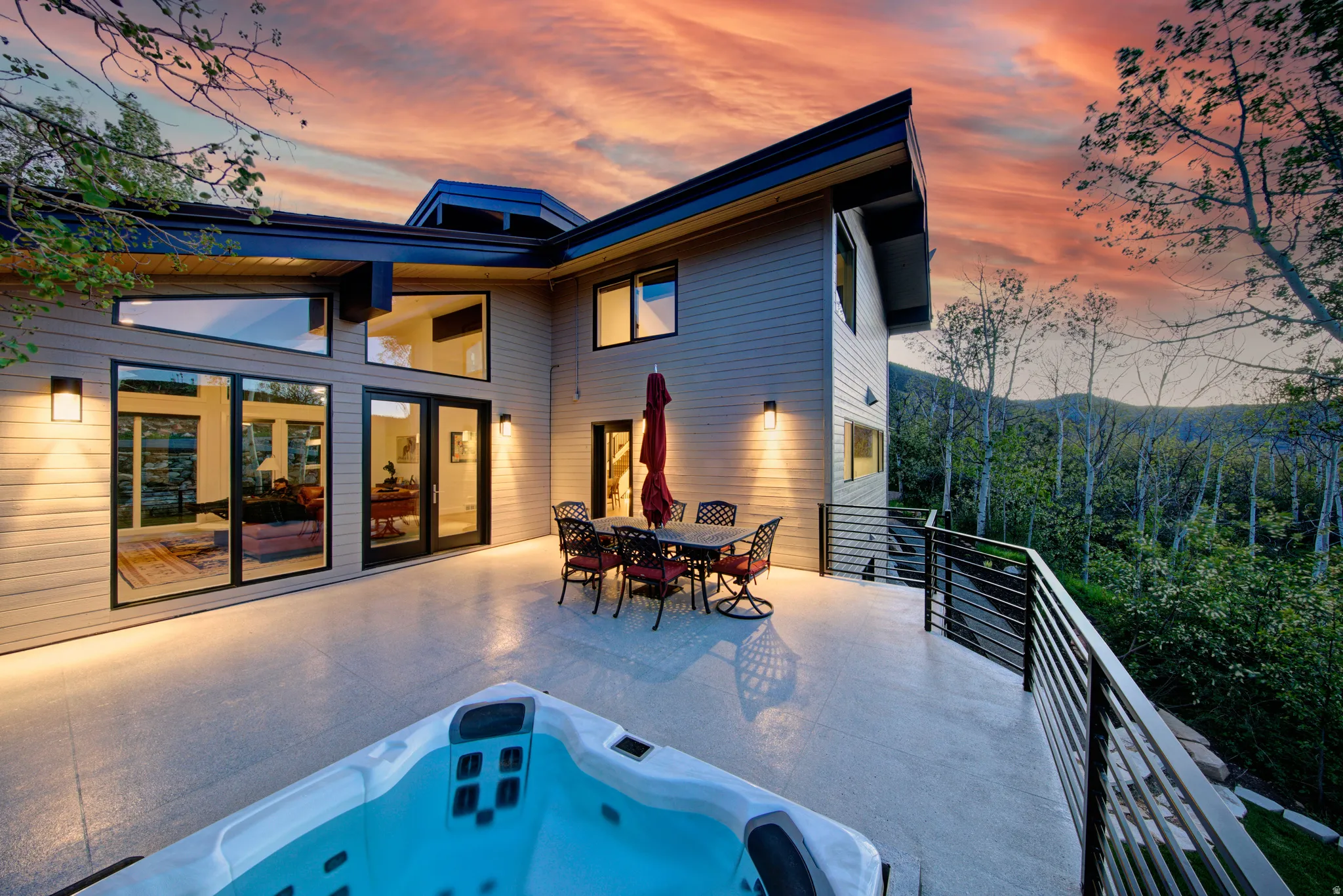 Expansive outdoor deck featuring an integrated hot tub, modern horizontal railings, and a serene mountainous backdrop wih exceptional privacy!