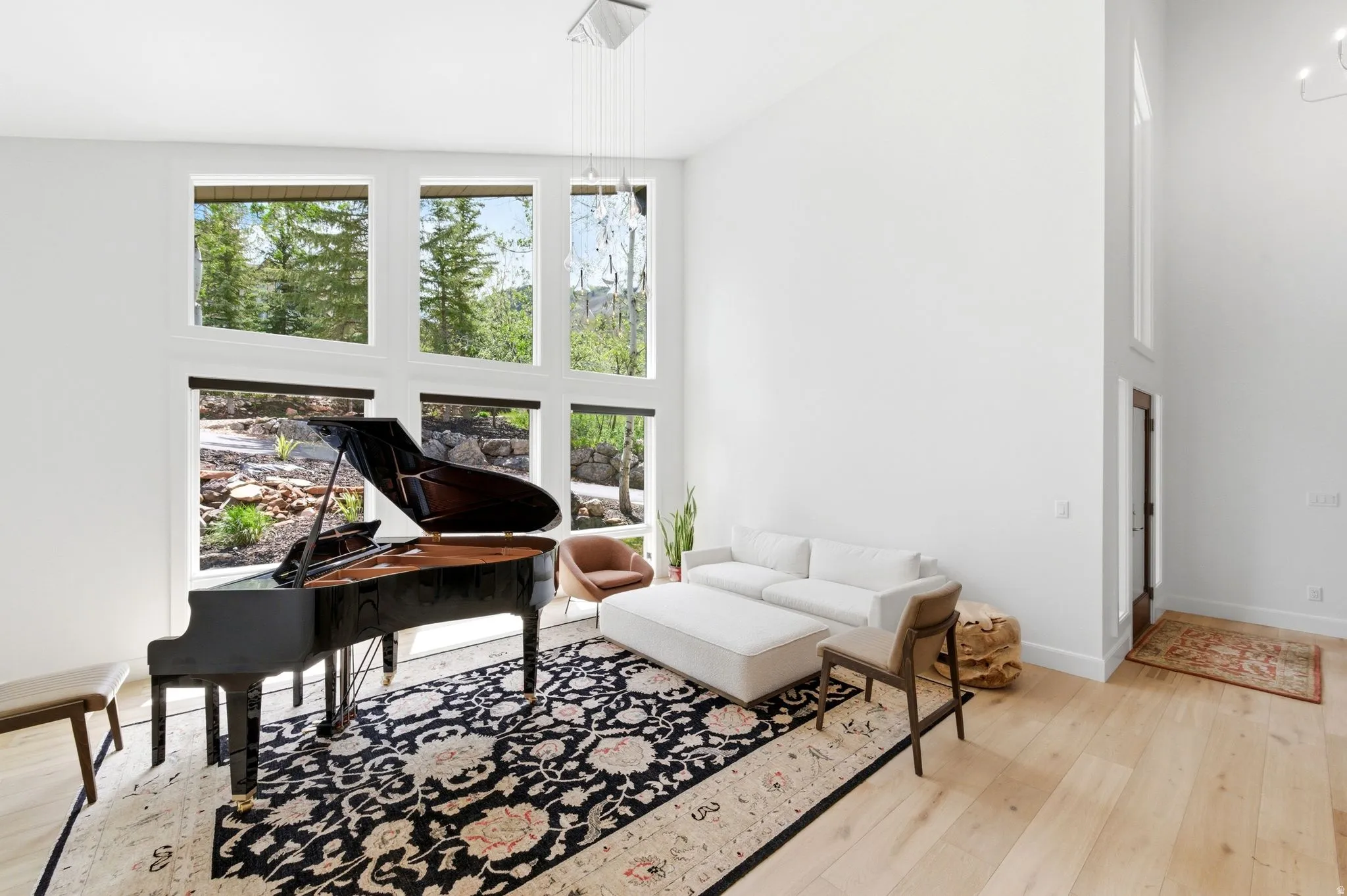 Spacious room with high ceilings, light wood-finish flooring, and expansive windows