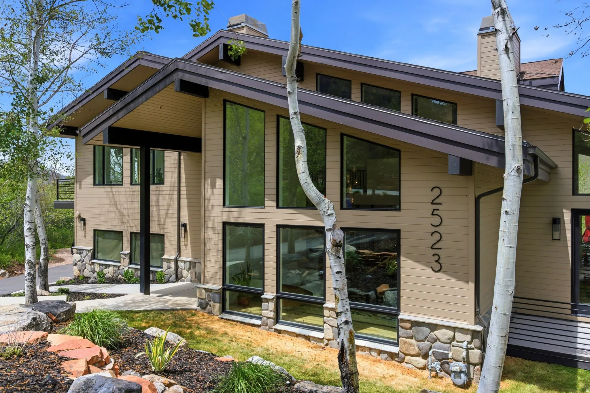 Modern architectural style featuring large, multi-pane windows and a stone foundation