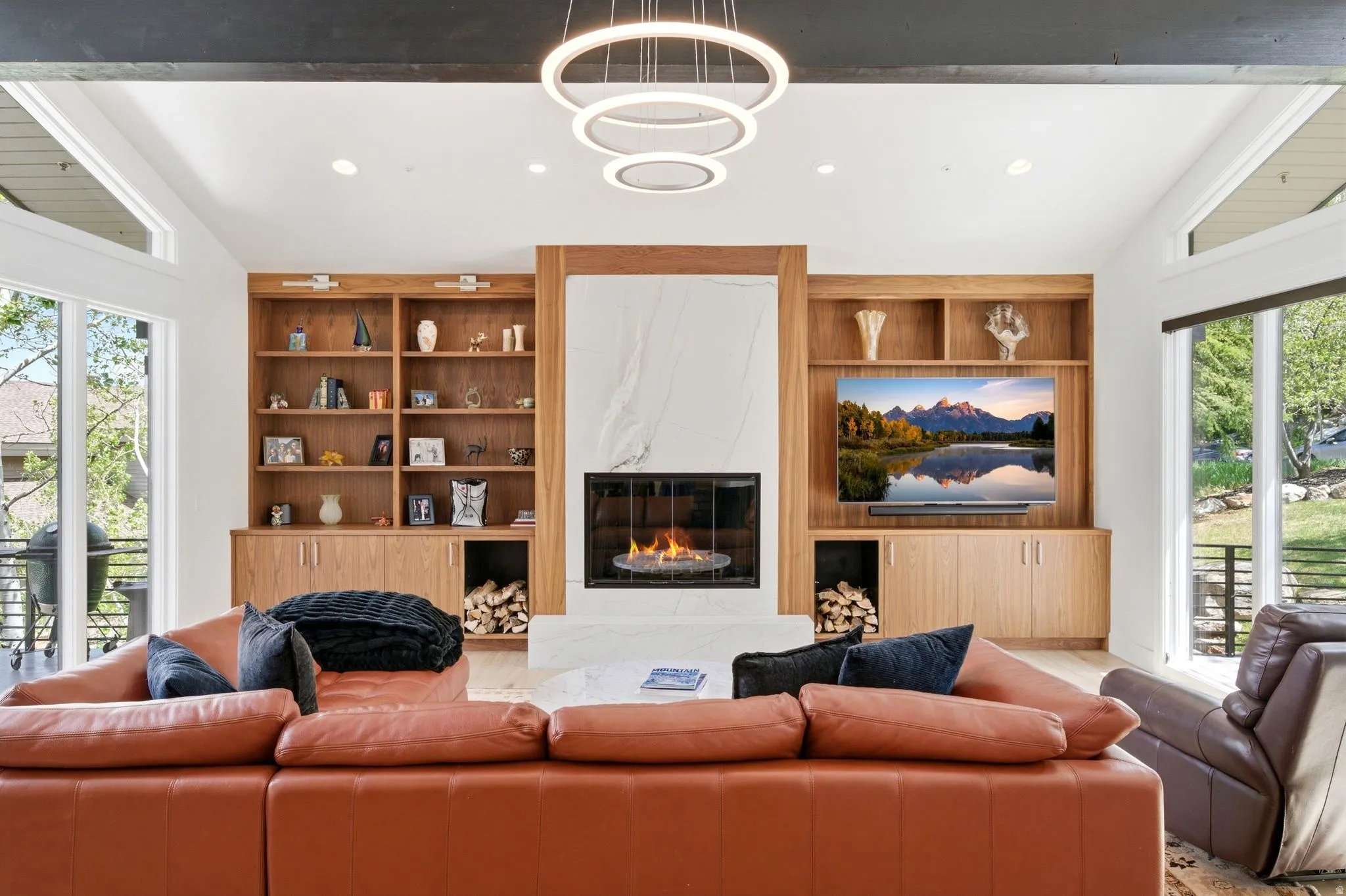 Living area featuring a contemporary fireplace with a stone surround, flanked by built-in wood cabinetry and shelving
