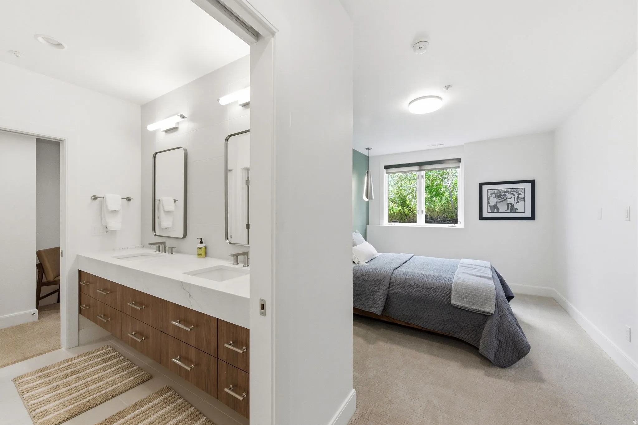 Dual vanity bathroom featuring a wood-finish floating cabinet with extensive storage, two rectangular sinks, and an expansive countertop