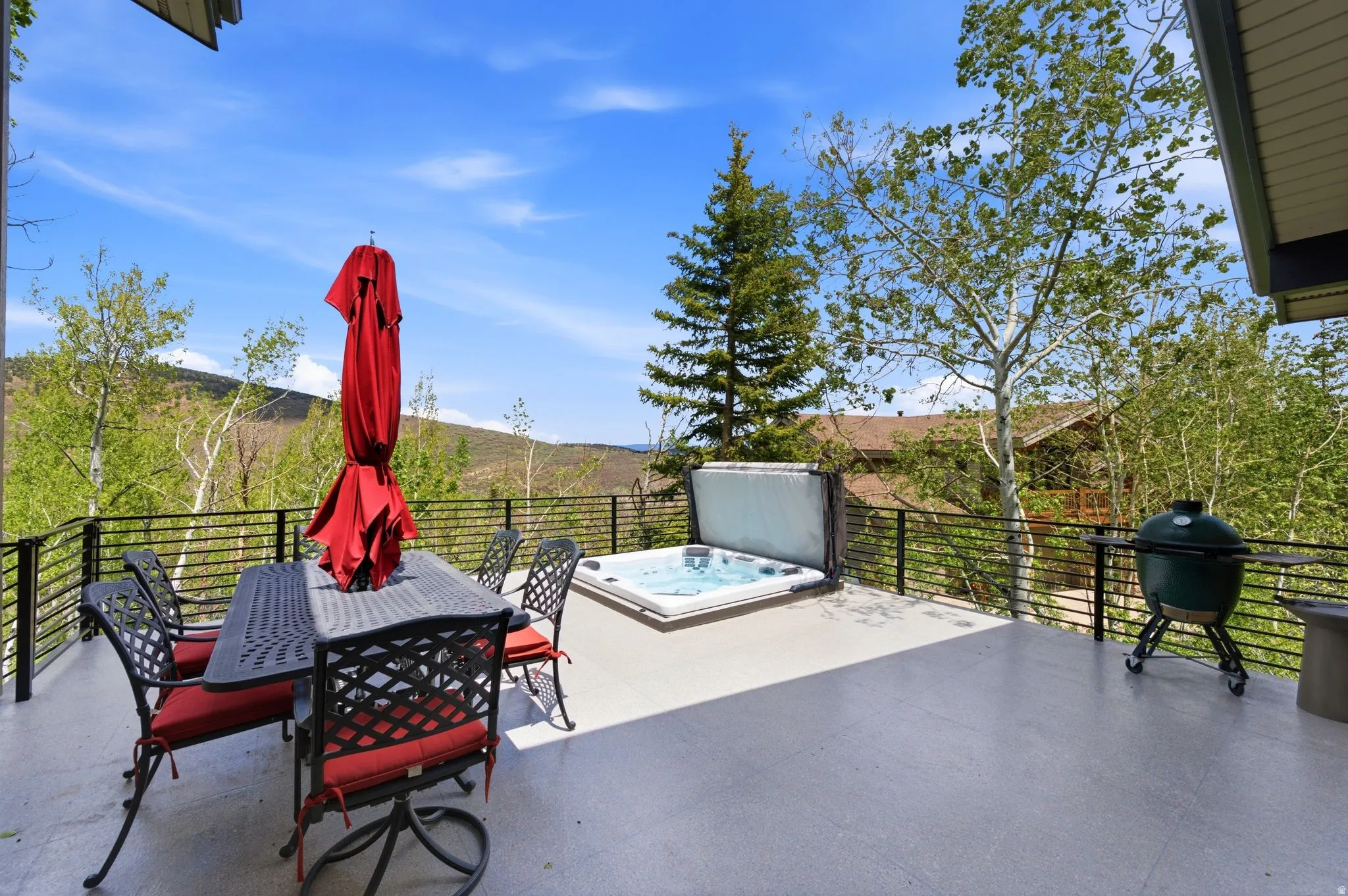 Spacious outdoor deck featuring a hot tub, mountain scenery, and horizontal metal railings