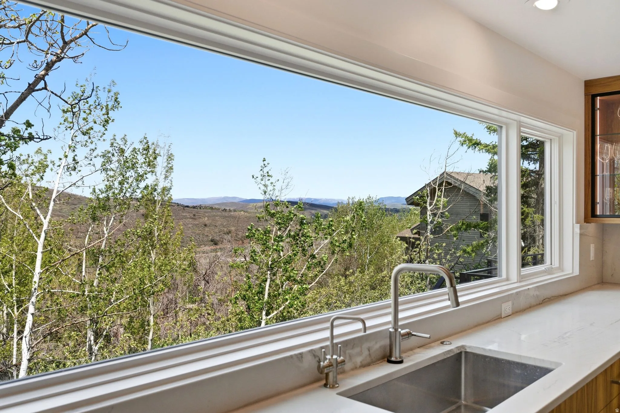 Expansive kitchen window framing a natural landscape with distant mountains