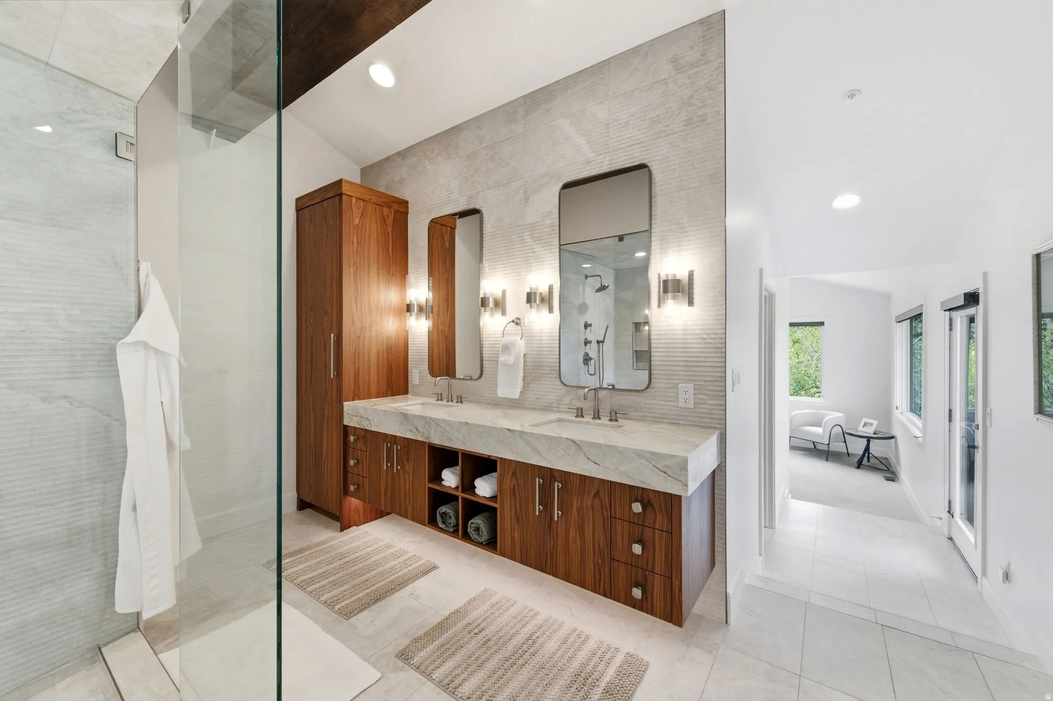 Dual vanity with a stone countertop and integrated sinks, complemented by contemporary mirrors and sconces