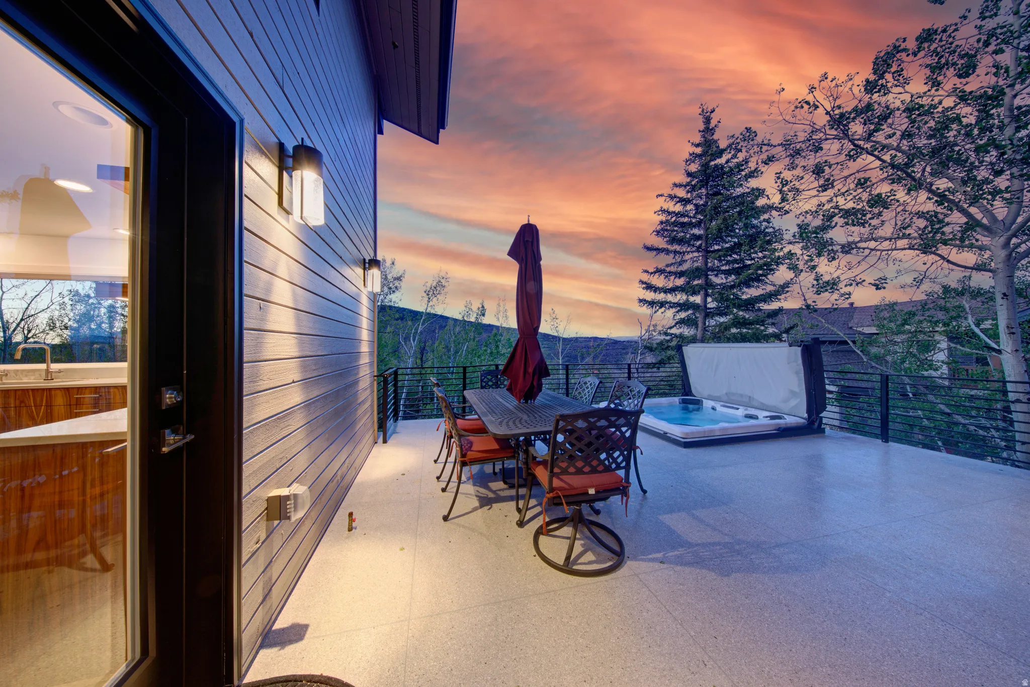 Expansive outdoor deck featuring a built-in spa, durable exterior siding, and a sliding glass patio door