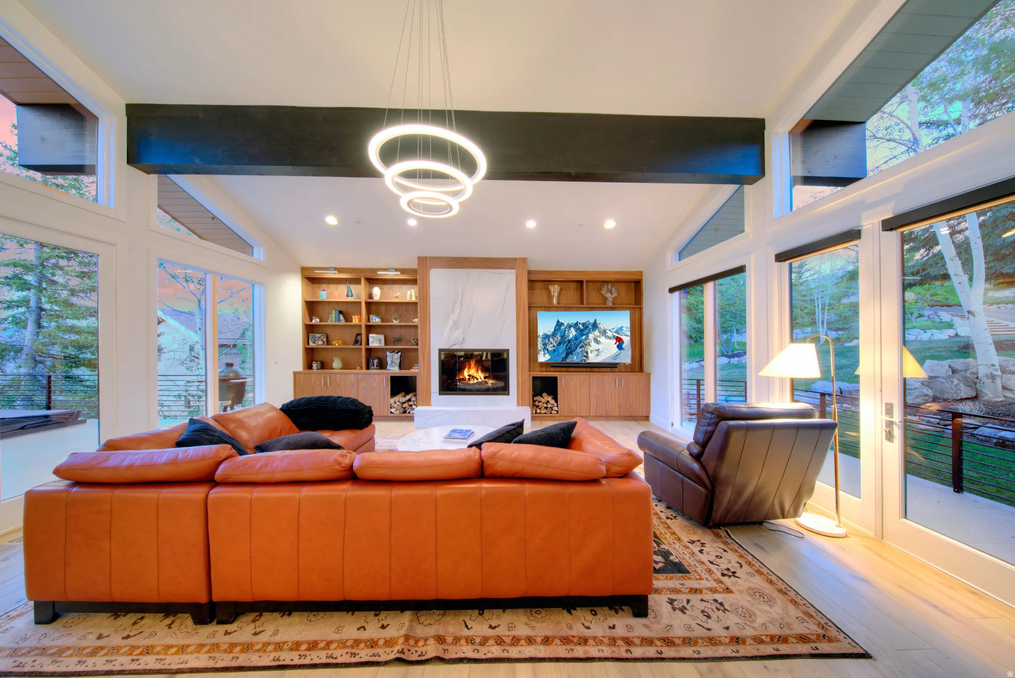 Spacious living area featuring high ceilings, a contemporary chandelier, and light wood-finish flooring