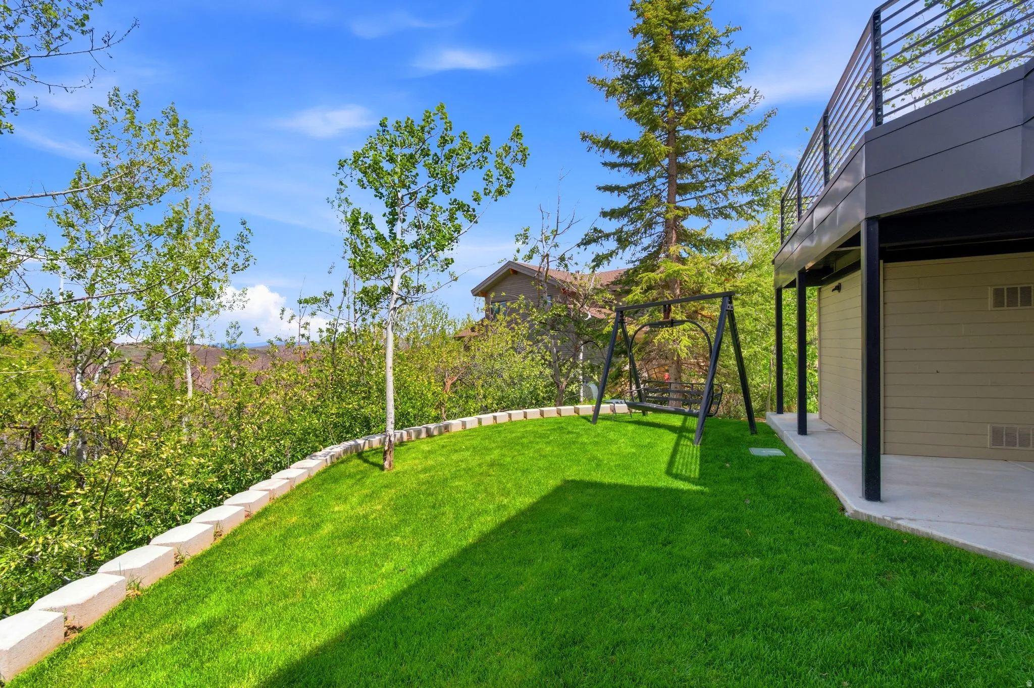 Expansive manicured lawn bordered by a stone retaining wall and mature trees