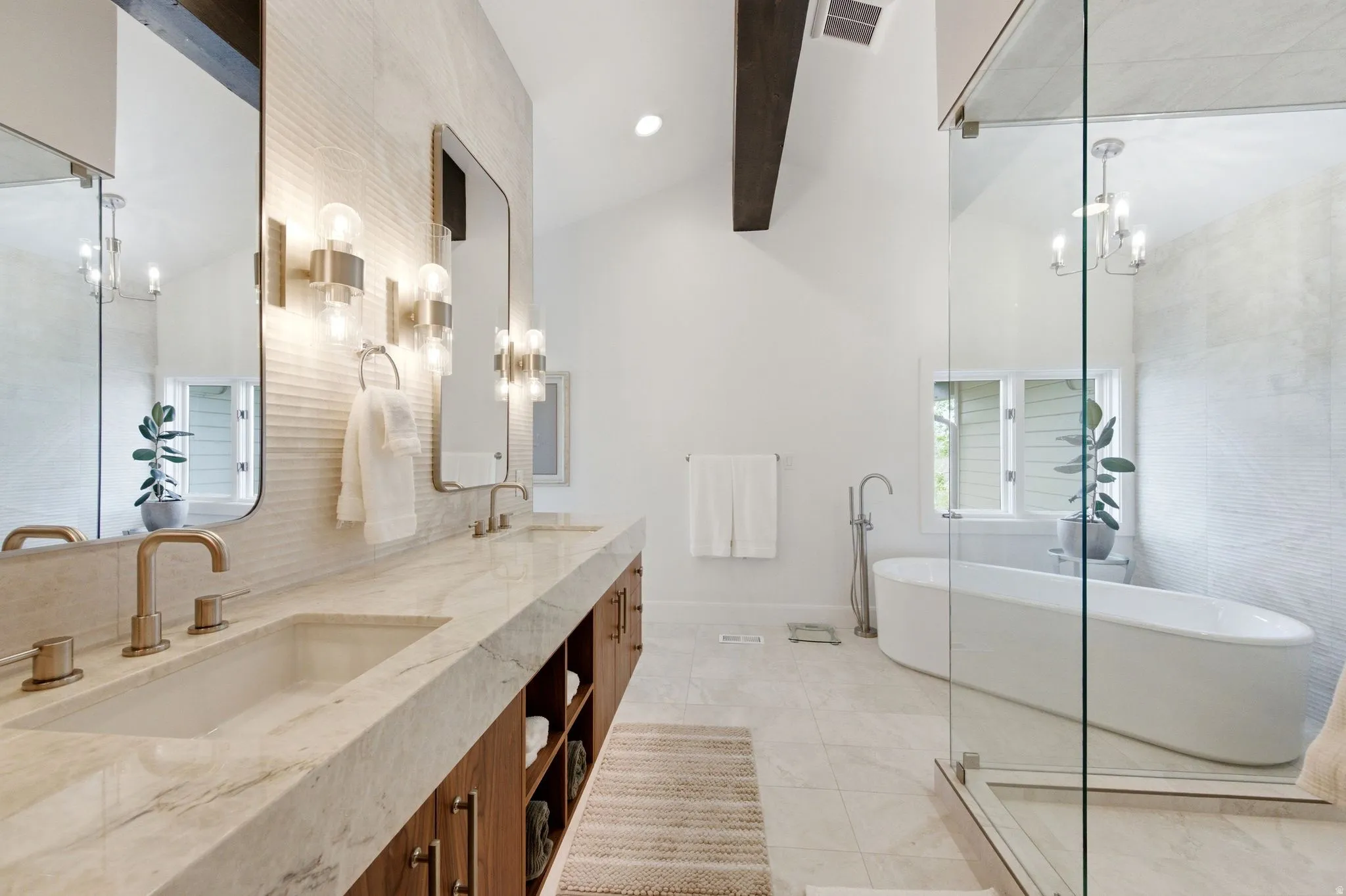 Bathroom featuring a freestanding soaking tub, an expansive glass-enclosed shower, and a dual vanity with integrated sinks