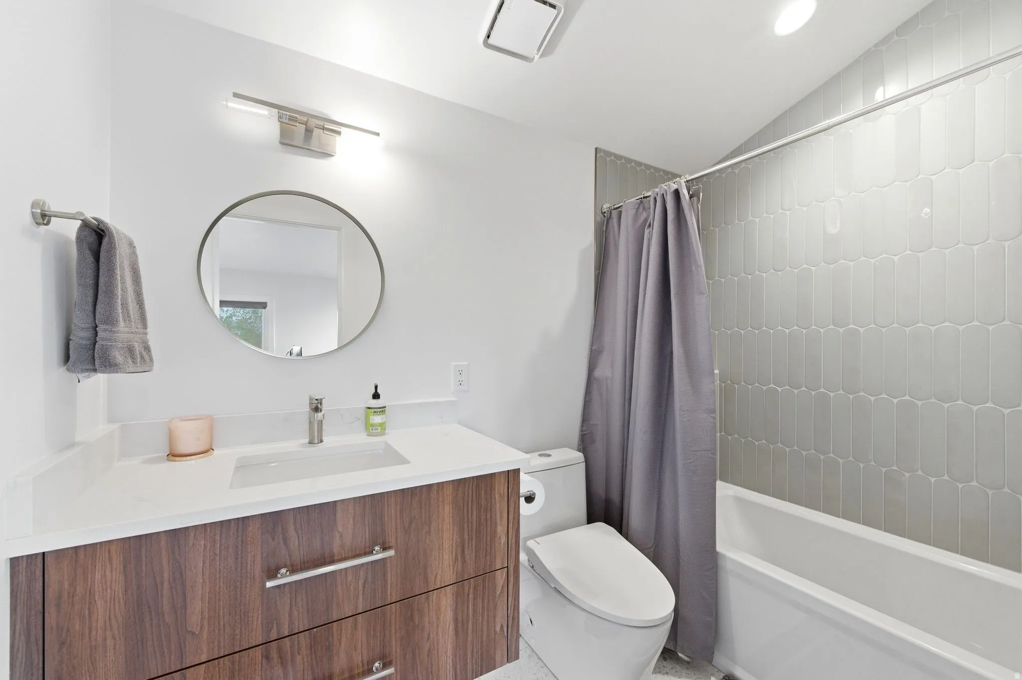 Bathroom featuring a modern vanity with wood-finish cabinetry, a white countertop, and an integrated sink