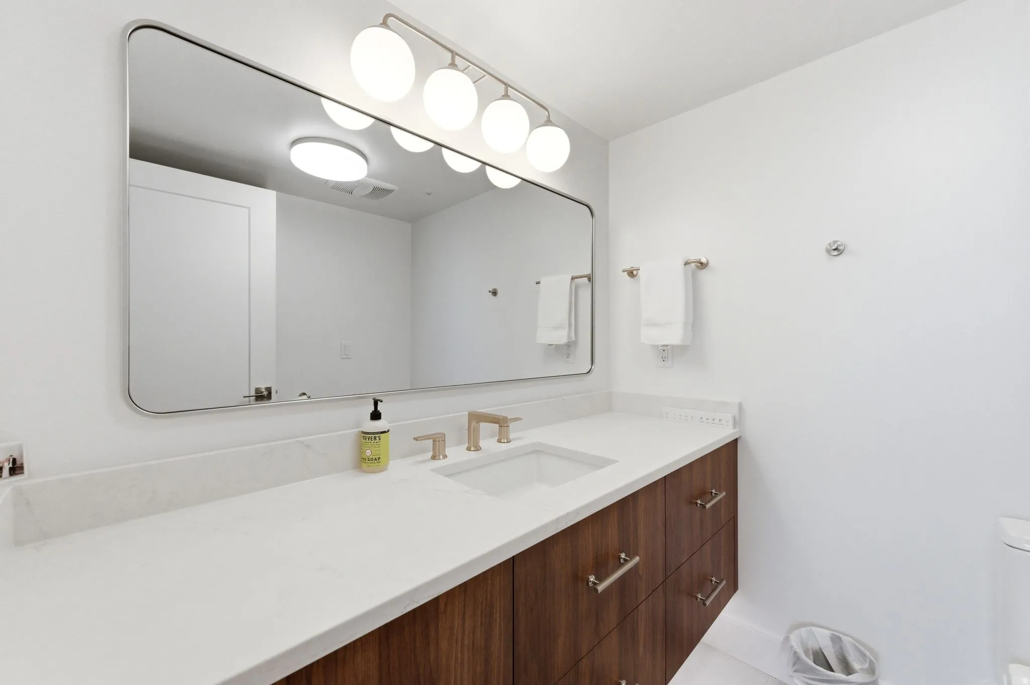 Contemporary bathroom vanity featuring a quartz countertop with an integrated rectangular sink