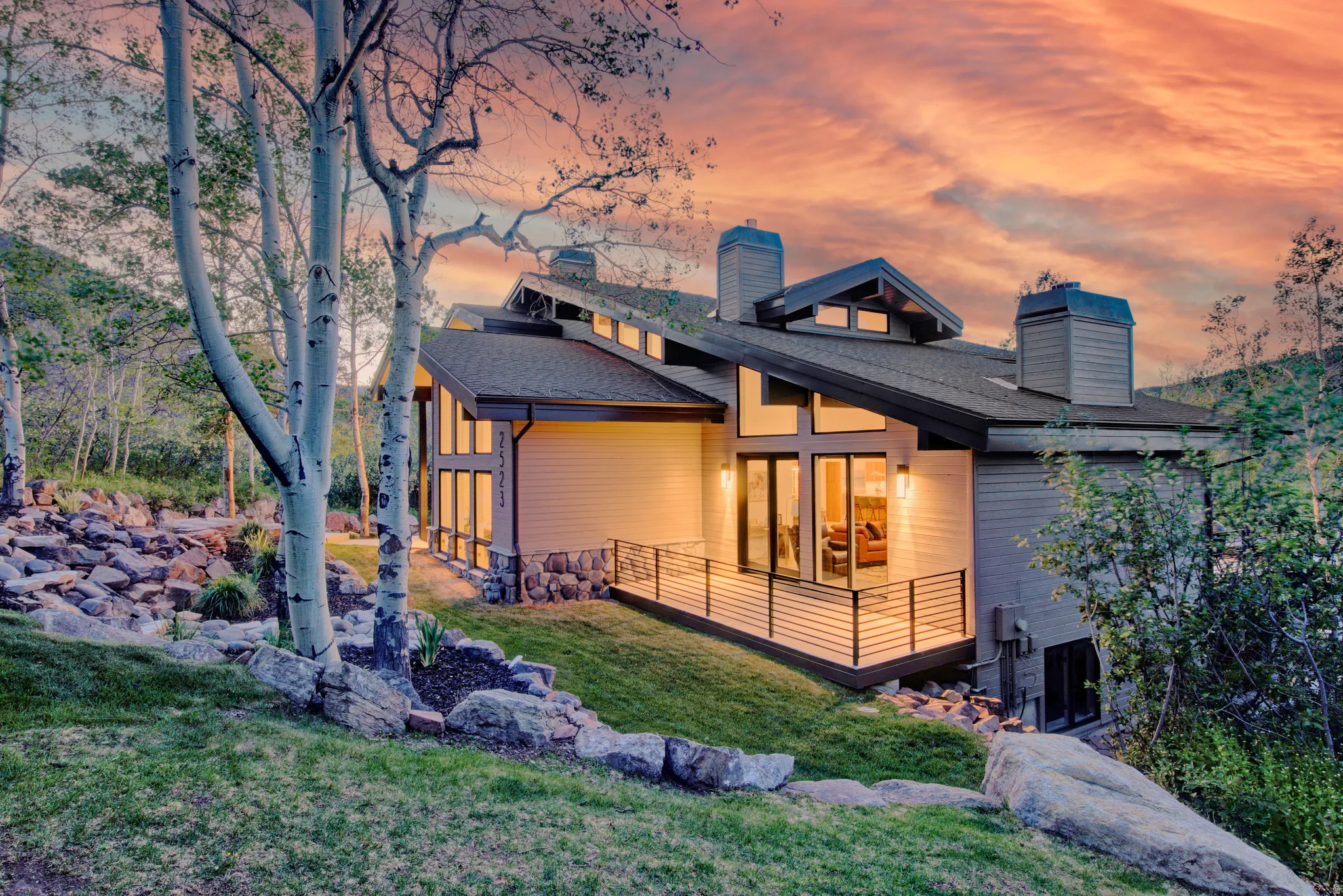 Modern mountain-style residence featuring a sloped dark roof and multiple chimneys